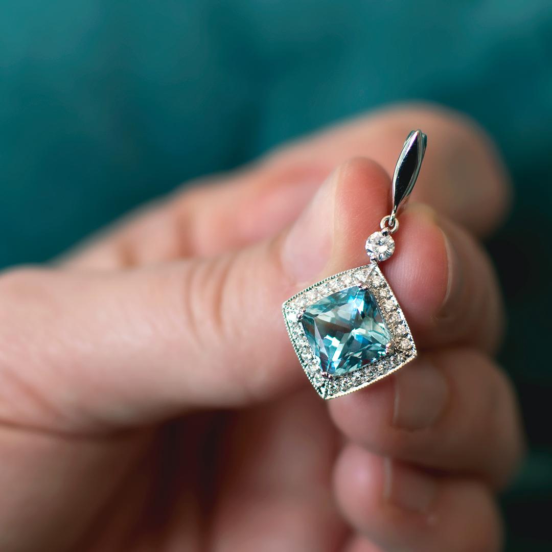 This detachable and very bright cushion Aquamarine with a weight of 3.63 Carat and Diamond Enhancer was handmade in a fine cluster milgrain setting. The total diamond weight is  0.39 Carat, Colour F/G, Clarity VS. Can be worn with a gold necklace or