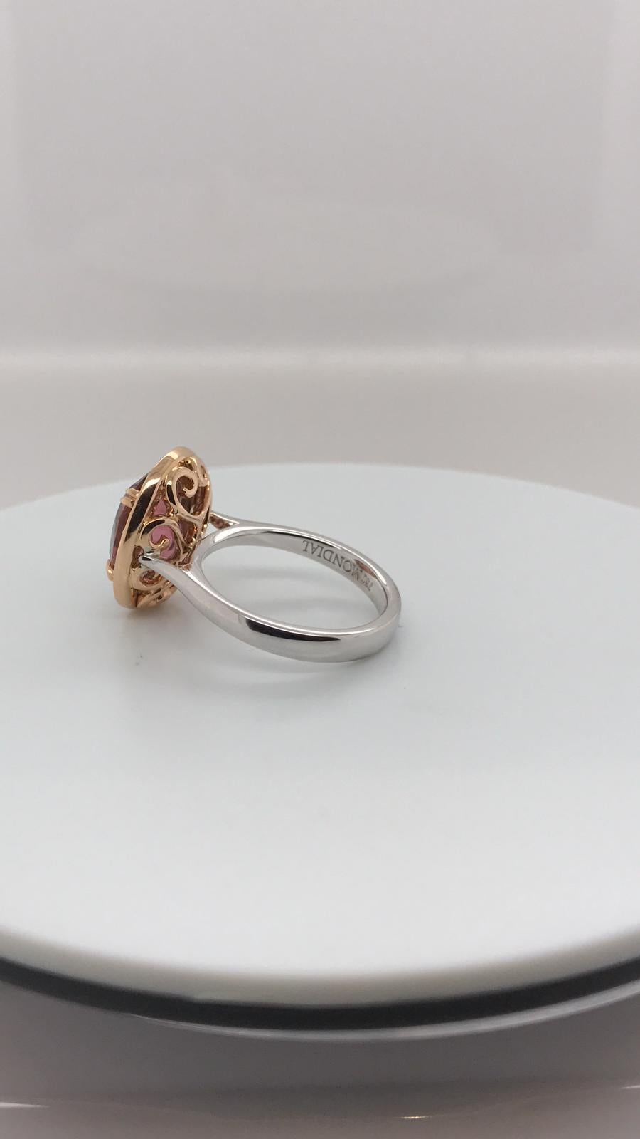 One Oval cut, 3.63ct Salmony Pink Tourmaline, claw set in 18k rose gold, surrounded by a halo of bead set brilliant cut white diamonds 28 = 0.34ct F in colour, VS in clarity, suspended on an 18ct rose gold filigree basket and a plain 18k white gold,