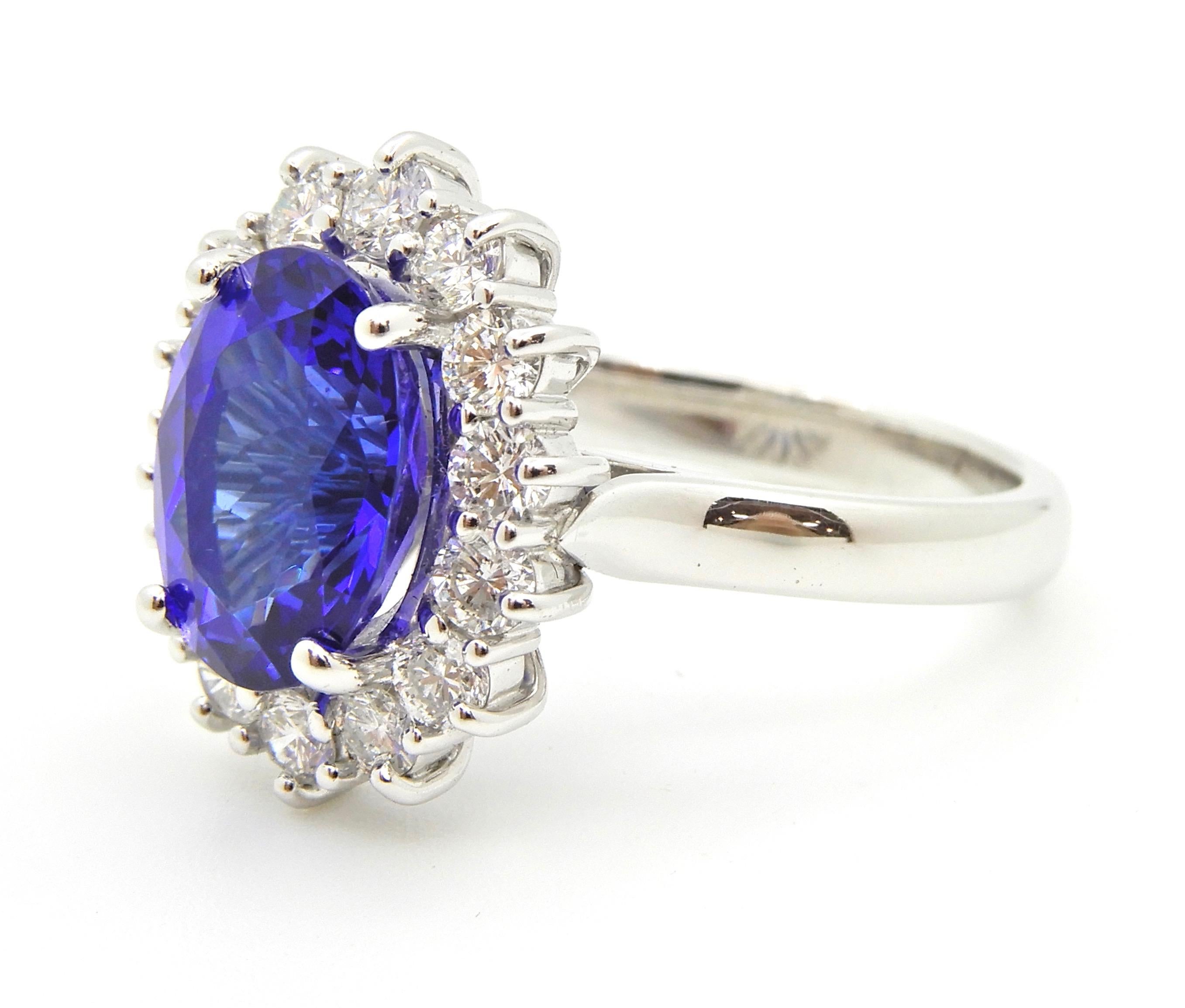This 3.63 Carat Oval Cut Tanzanite and Diamond Handmade Ring is set in 18 carat white gold. The rounded, flat edge band which splits into an underrail and upswept shoulders supports a 14 wire basket holding the central 4 claw set oval Tanzanite