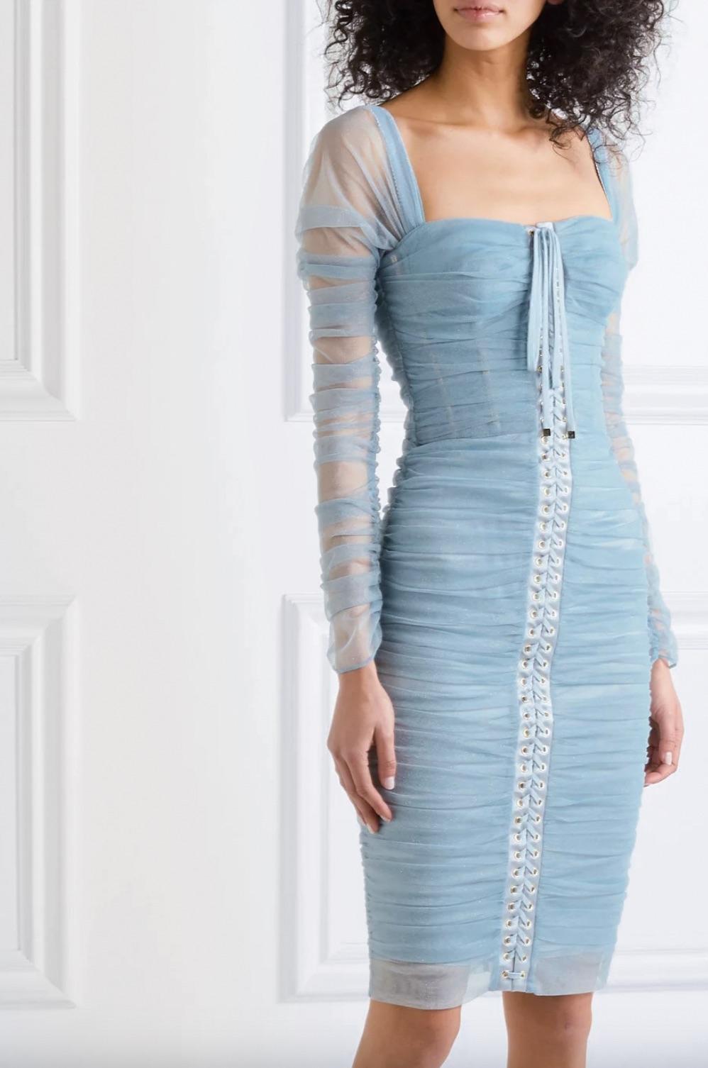 The lace-up tulle bustier dress by Dolce & Gabbana is a stunning piece crafted in Italy. It is made of sheer blue tulle and features a sweetheart neckline, long sleeves, and a knee-length fitted silhouette. The dress has a feminine ruched effect