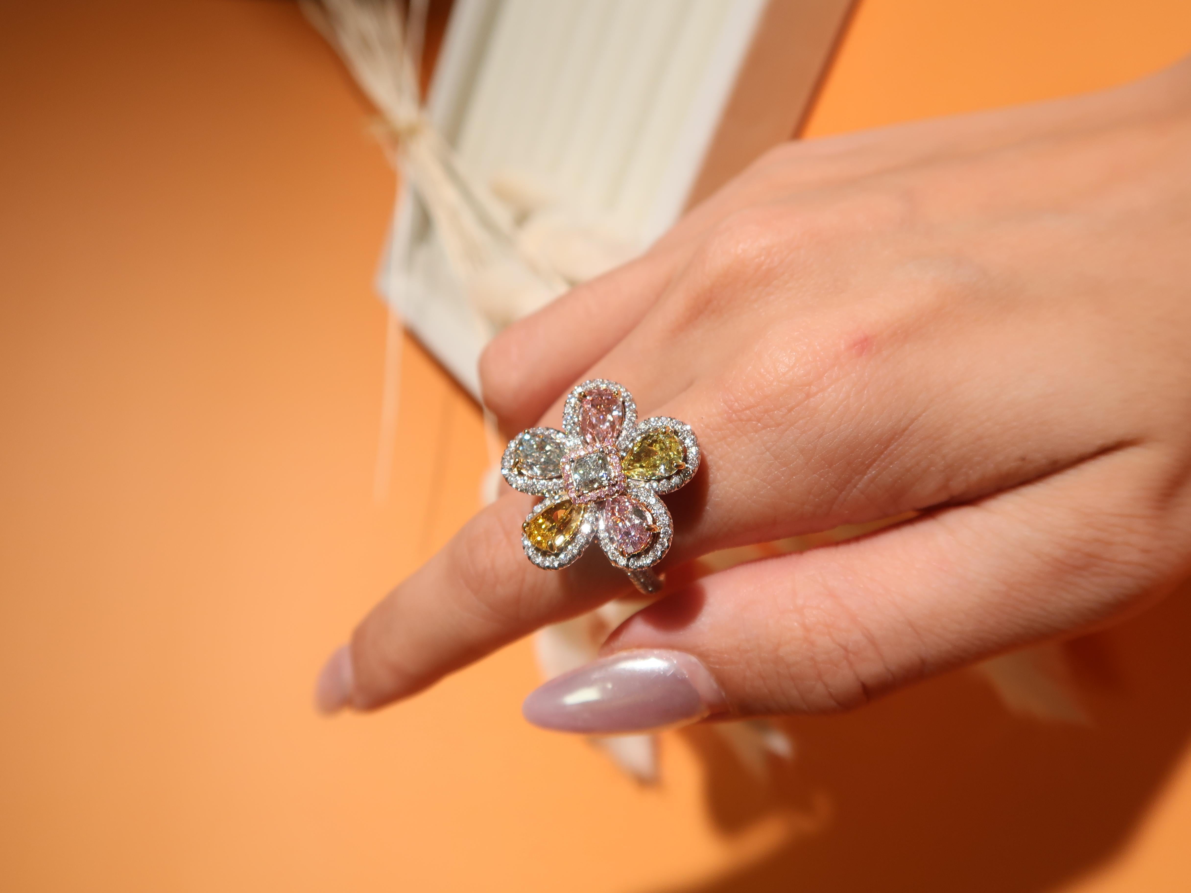 A multi-color floral diamond ring featuring a vibrant array of diamonds: a 0.36 carat green cushion-shaped diamond at its center, surrounded by 20 round-shaped pink diamonds weighing 0.06 carat. this ring include a 0.56 carat pear-shaped fancy