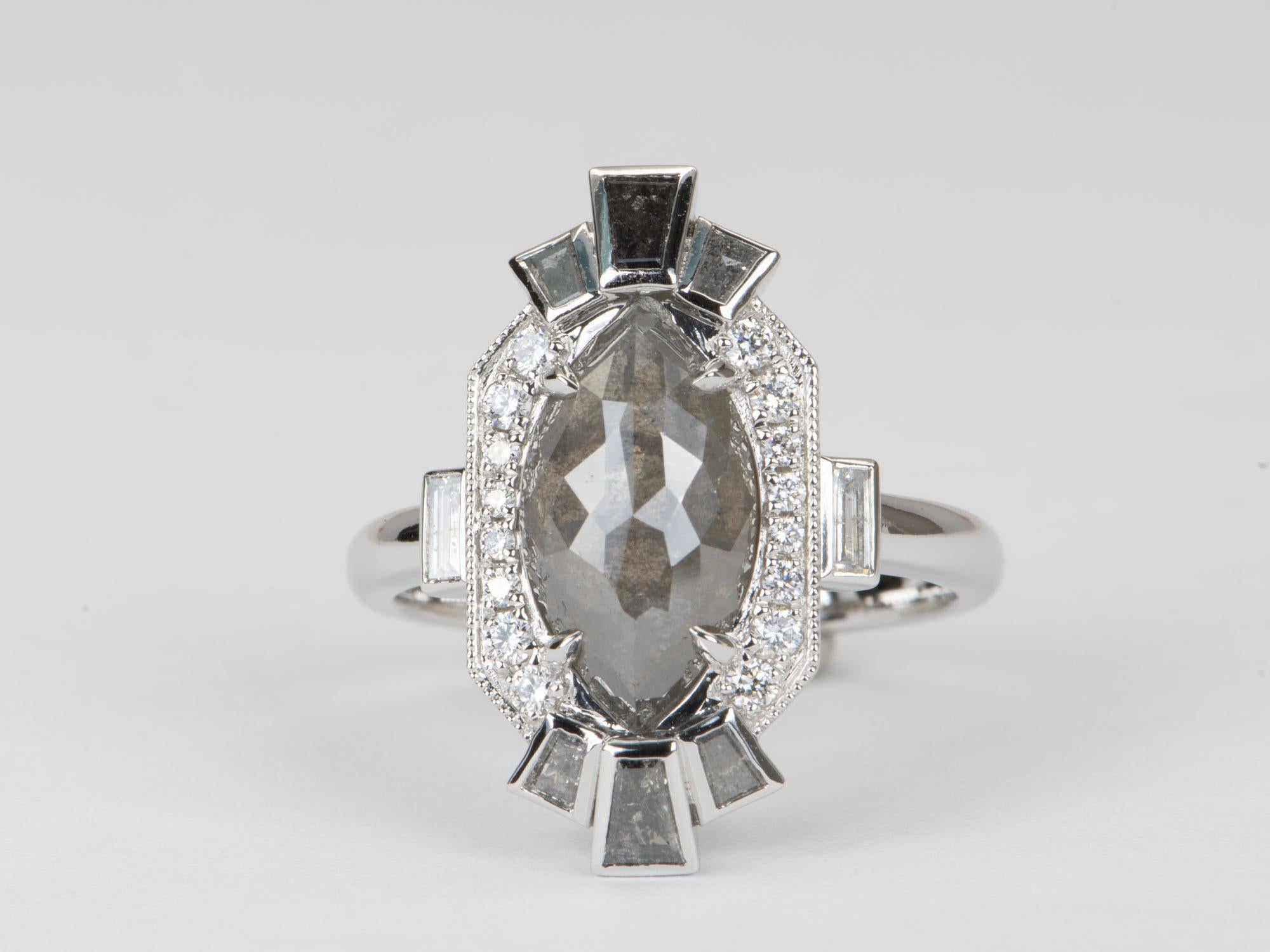 This one-of-a-kind statement ring boasts a 3.66ct salt and pepper diamond set in luxurious 14K white gold, surrounded by a unique halo of tapered baguette and round brilliant cut diamonds. The ring's stunning design makes it an exquisite piece of