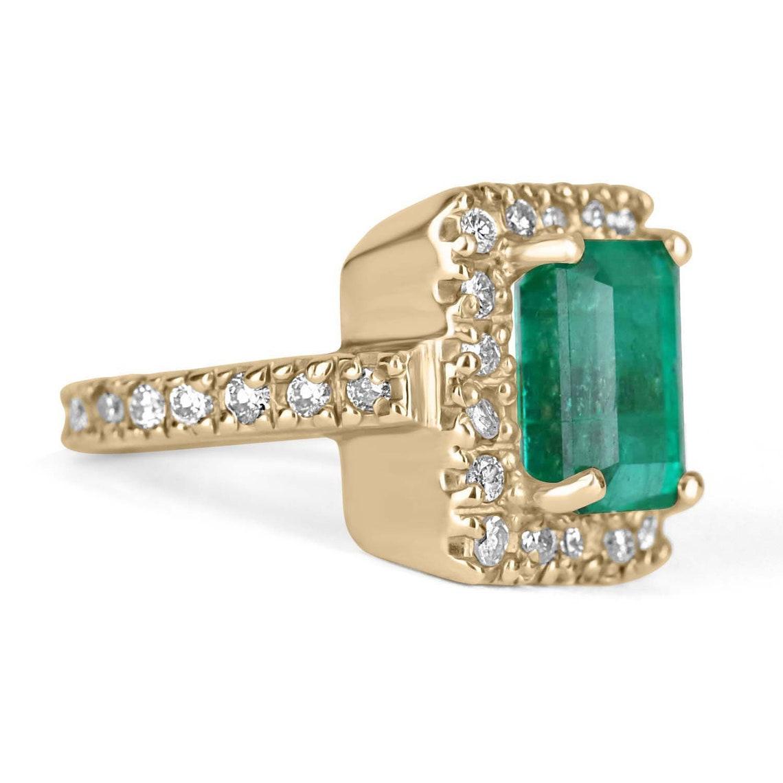 Displayed is a vintage Colombian emerald and diamond halo ring. The center gem is an emerald cut emerald filled with life and brilliance! Among the impressive qualities of the emerald, a vivid green color and beautiful eye clarity are seen. Small