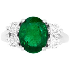 oval diamond with emerald side stones Oval Emerald and Diamond Side Stone Engagement Ring
