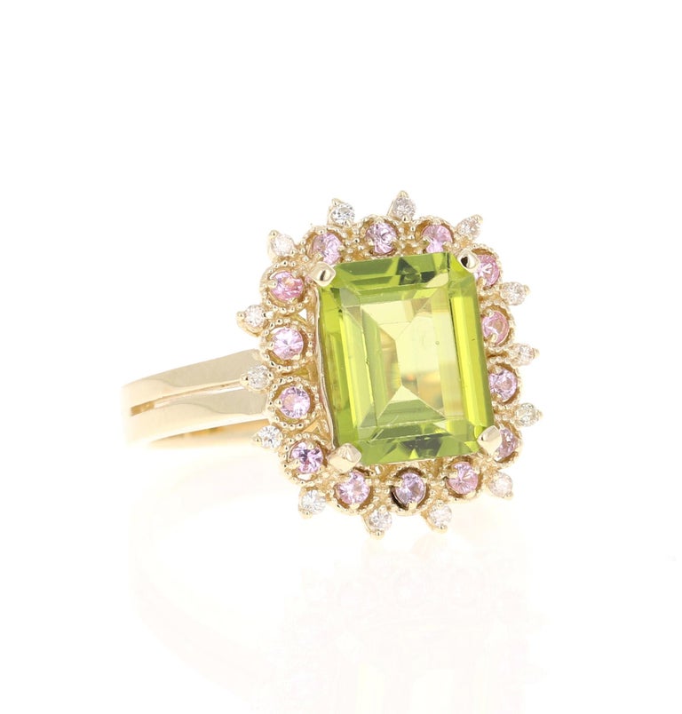 This beautiful ring has an Emerald Cut Peridot that weighs 3.30 Carats. The ring is surrounded by 14 Pink Sapphires that weigh 0.26 Carats and 14 Round Cut Diamonds that weigh 0.12 Carats. (Clarity: SI, Color: H)  The total carat weight of this ring