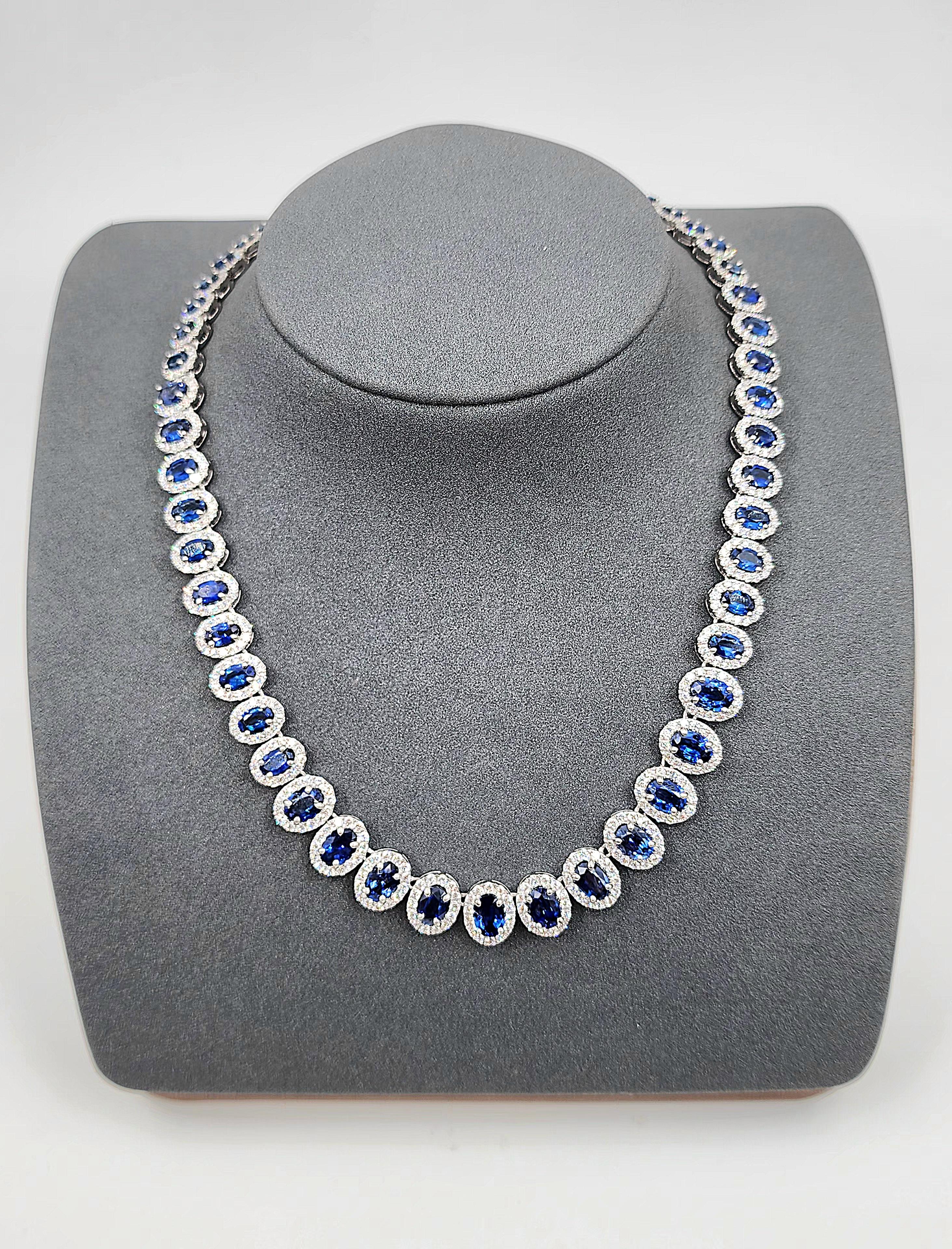This stunning natural sapphire and diamond necklace is sure to turn heads. The necklace features 55 graduated oval sapphires weighing a total of 27.03 carats, and 721 round diamonds weighing 9.58 carats. The diamonds are of E/F color and VS clarity,