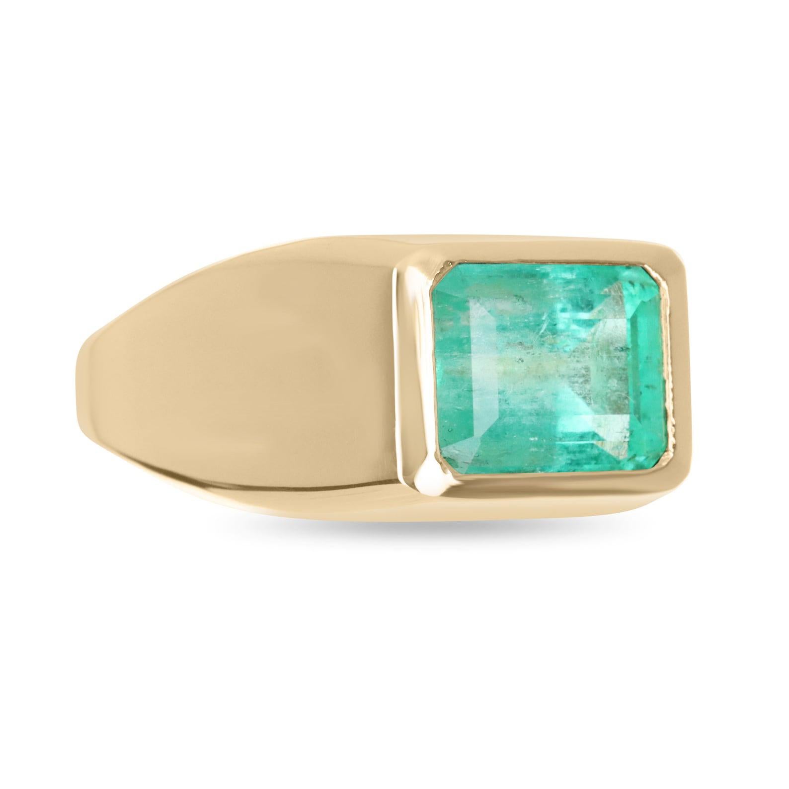 Displayed is a stunning, East to West, Colombian emerald signet bezel ring in 14K yellow gold. This gorgeous statement-size solitaire ring carries a 3.68-carat ethically mined emerald in a secure golden bezel setting. Fully faceted, this gemstone