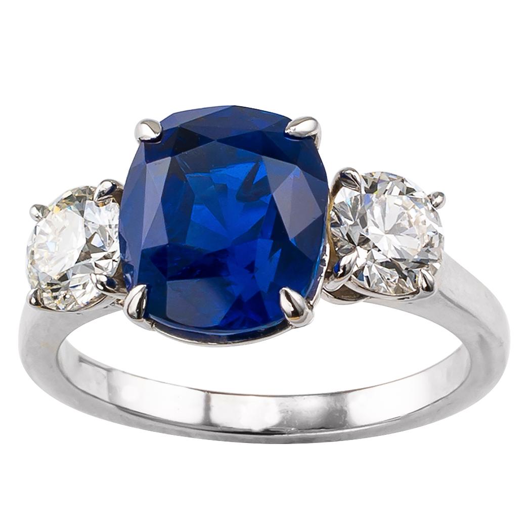 Ceylon sapphire 3.69 carats and GIA graded diamonds three-stone platinum ring. Centering upon a cushion-shaped 3.69 carats blue sapphire accompanied by a report from GIA stating that the sapphire is of Ceylon origin, between a pair of round