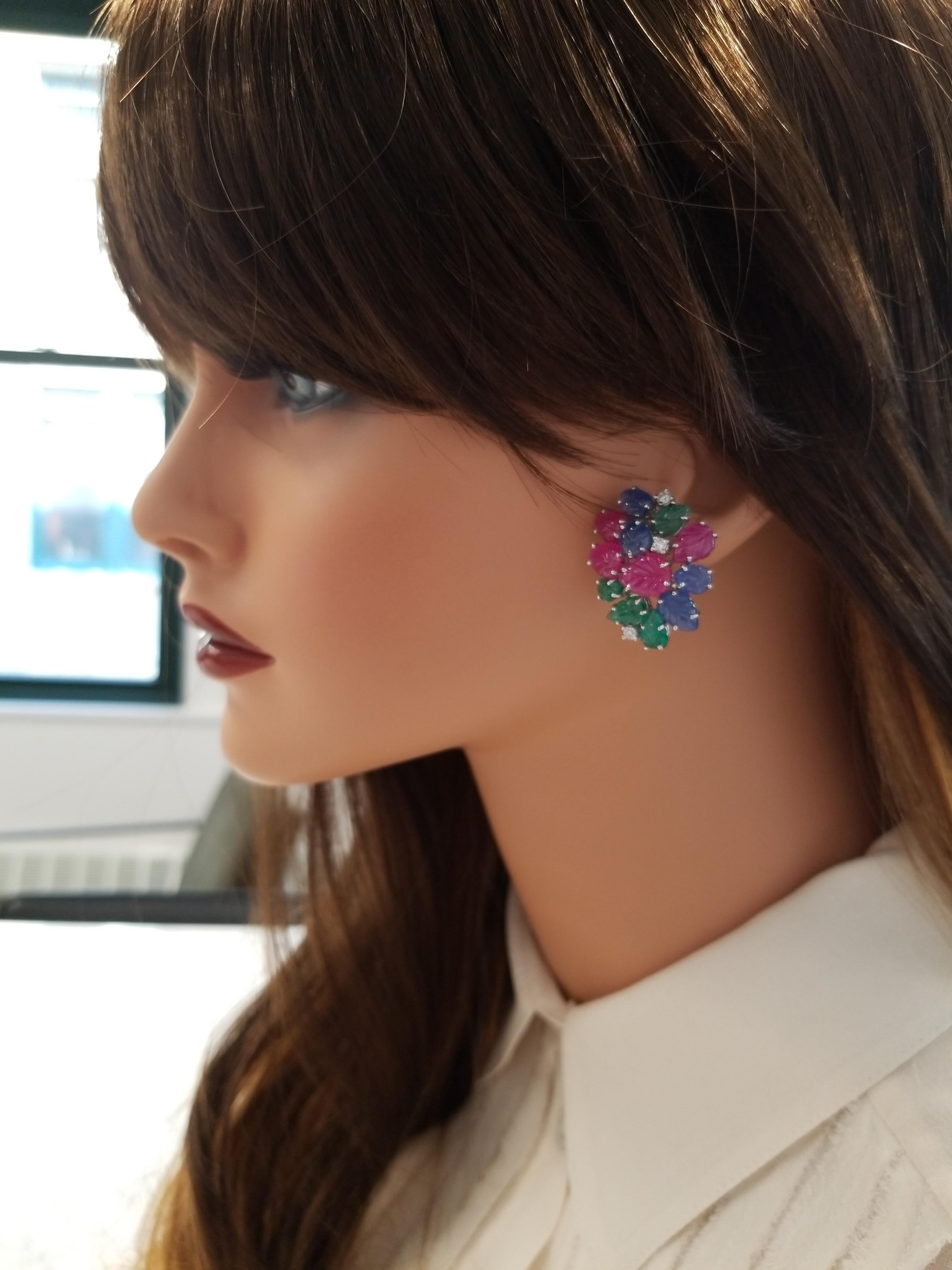 Sapphire, ruby, and emerald gracefully come together to make these gorgeous earrings in handcarved leaf shapes totaling an impressive 36.92 carats of vibrant colors and unique luxury. The skill of handcarving rubies, sapphires, and emeralds is a