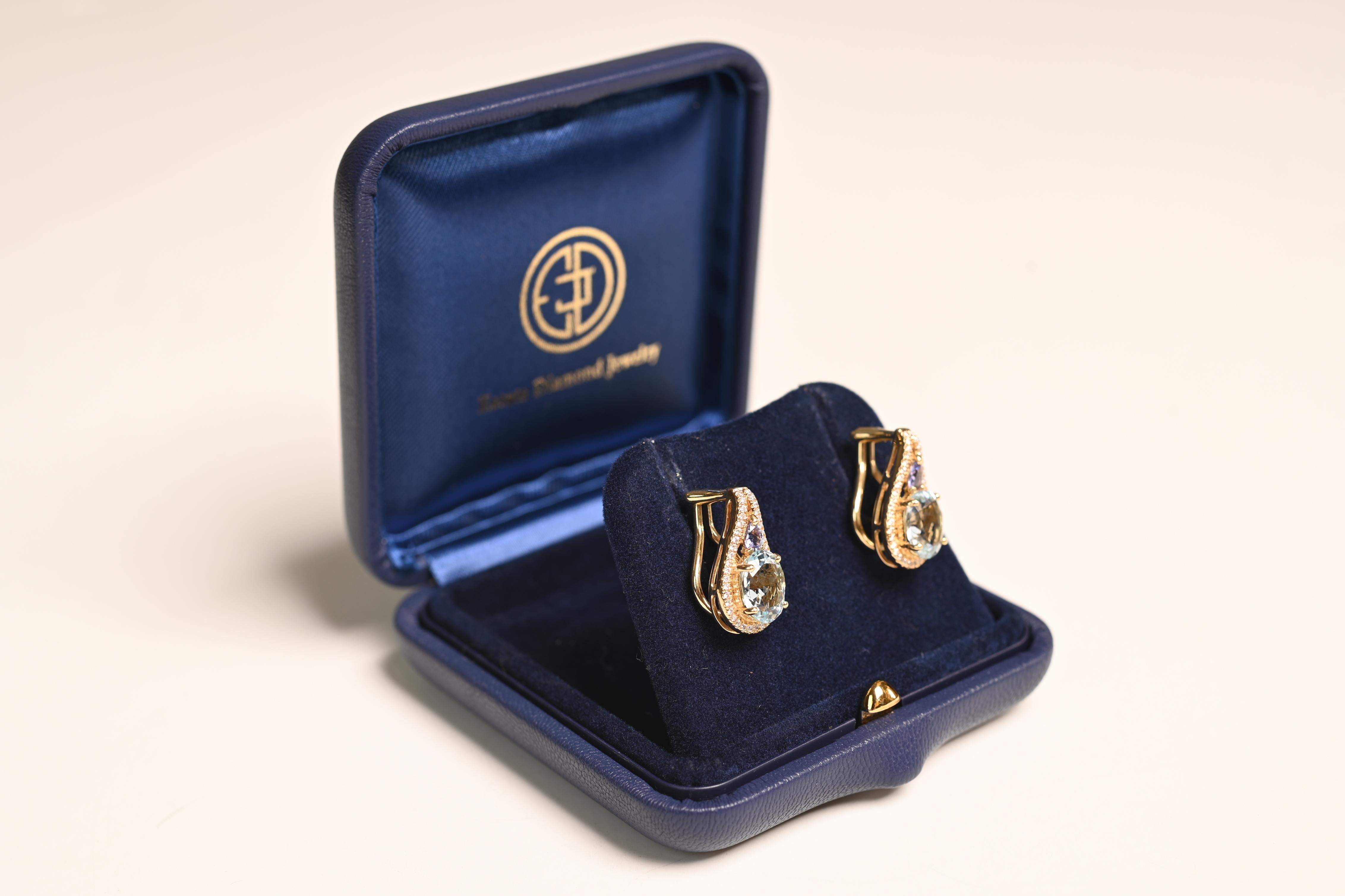 This exquisite pair of aquamarine and tanzanite earrings is a true testament to elegance and craftsmanship. Each earring showcases a mesmerizing oval-cut aquamarine, with a combined total weight of approximately 3.69 carats. The aquamarines exhibit
