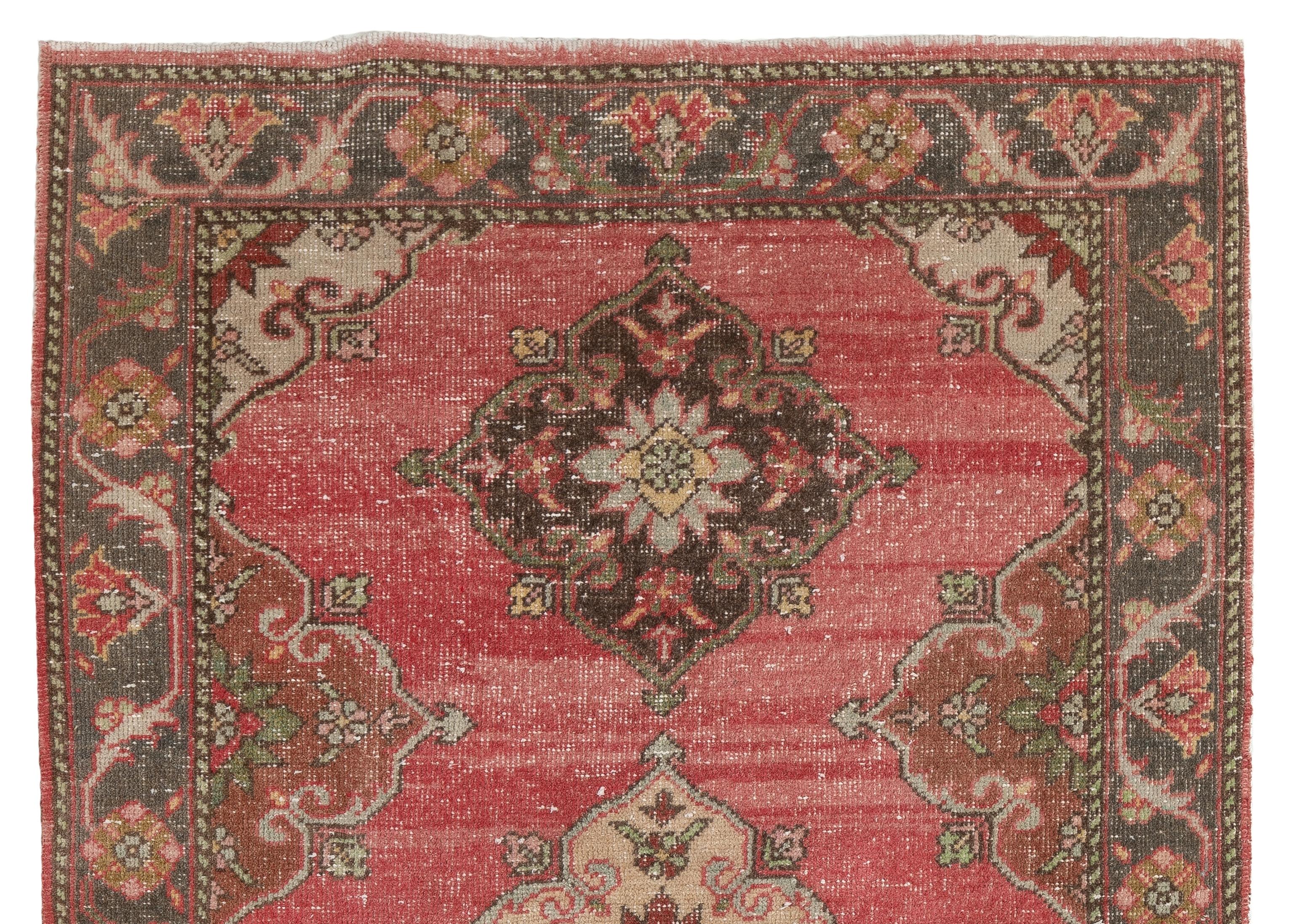 A finely hand-knotted vintage Turkish rug made in the 1960s with multiple full and half medallions in pale yellow, dark terra cotta red, charcoal grey against a red field. The rug has even low wool pile on cotton foundation. It is heavy and lays