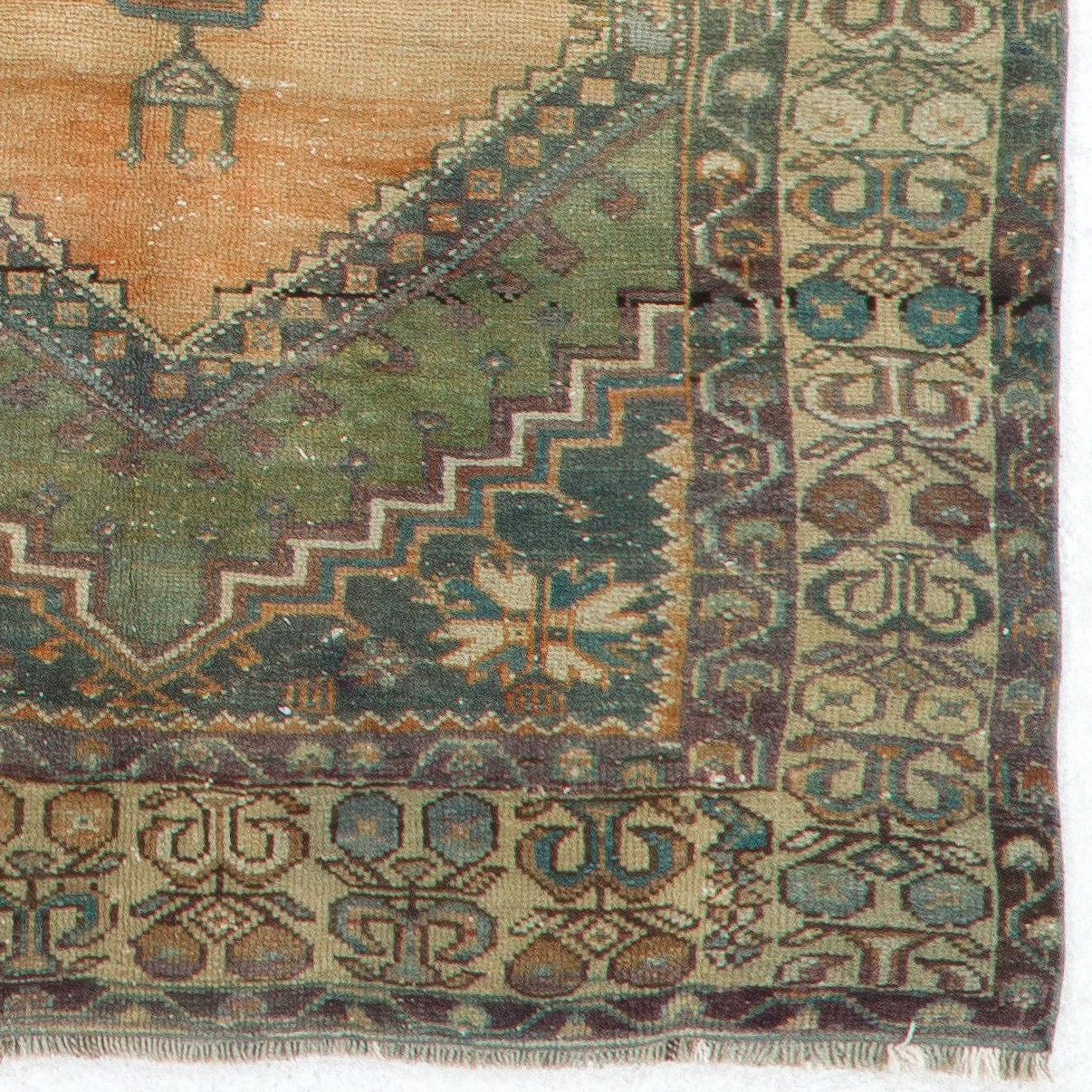 This vintage Central Anatolian rug features two linked medallions in deep-saturated gold with cross-shaped motifs inside against a plain field in soft muted soft red. The corner-pieces in charcoal gray are decorated with large, elongated palmettes.