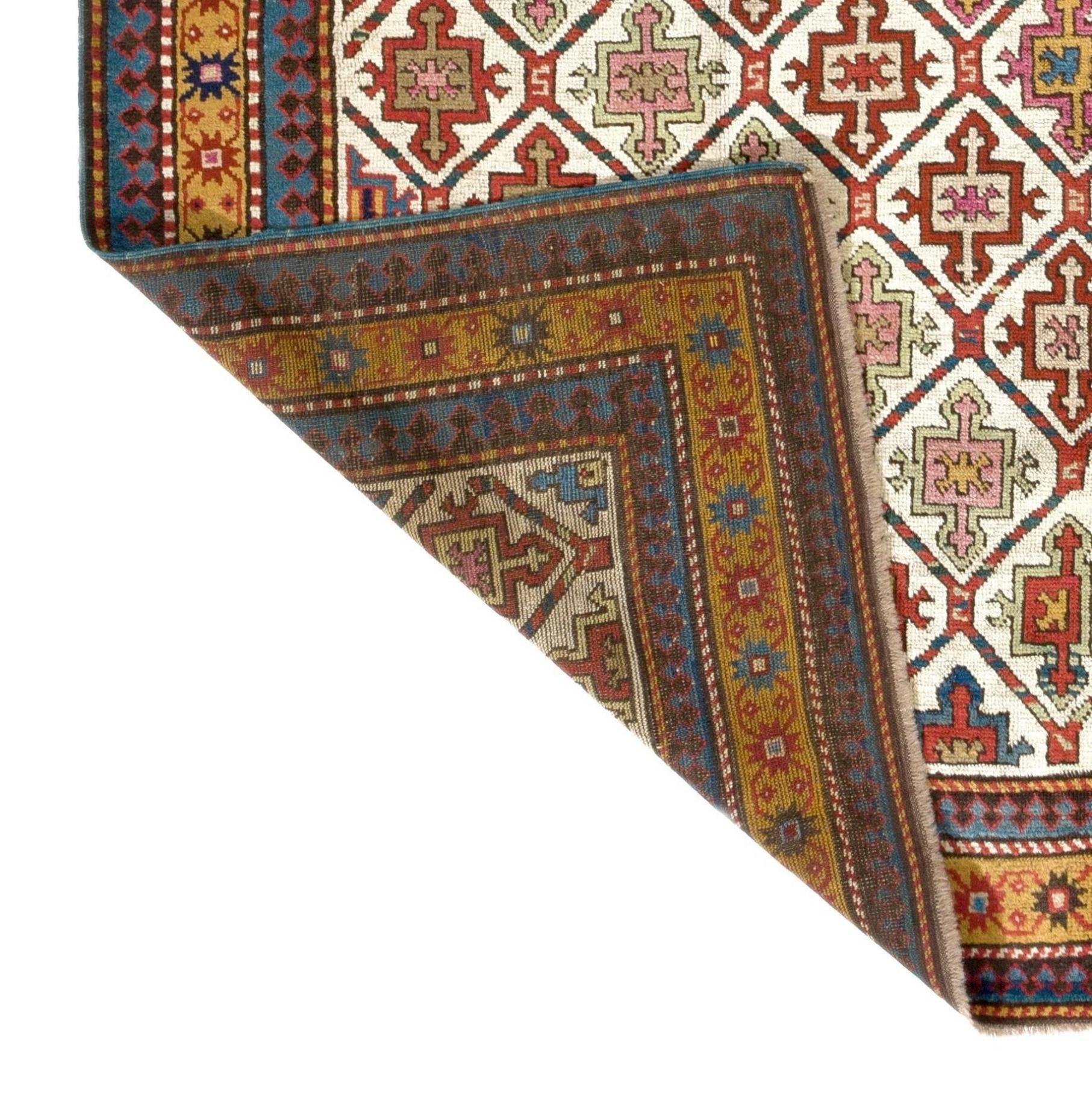 A rare and early Karabagh long rug from the first quarter of the 19th century featuring an all-over lattice work design with integrated shield and cross motifs in a subtle color palette of soft pink, sage green, beige, rust, navy blue and cerulean