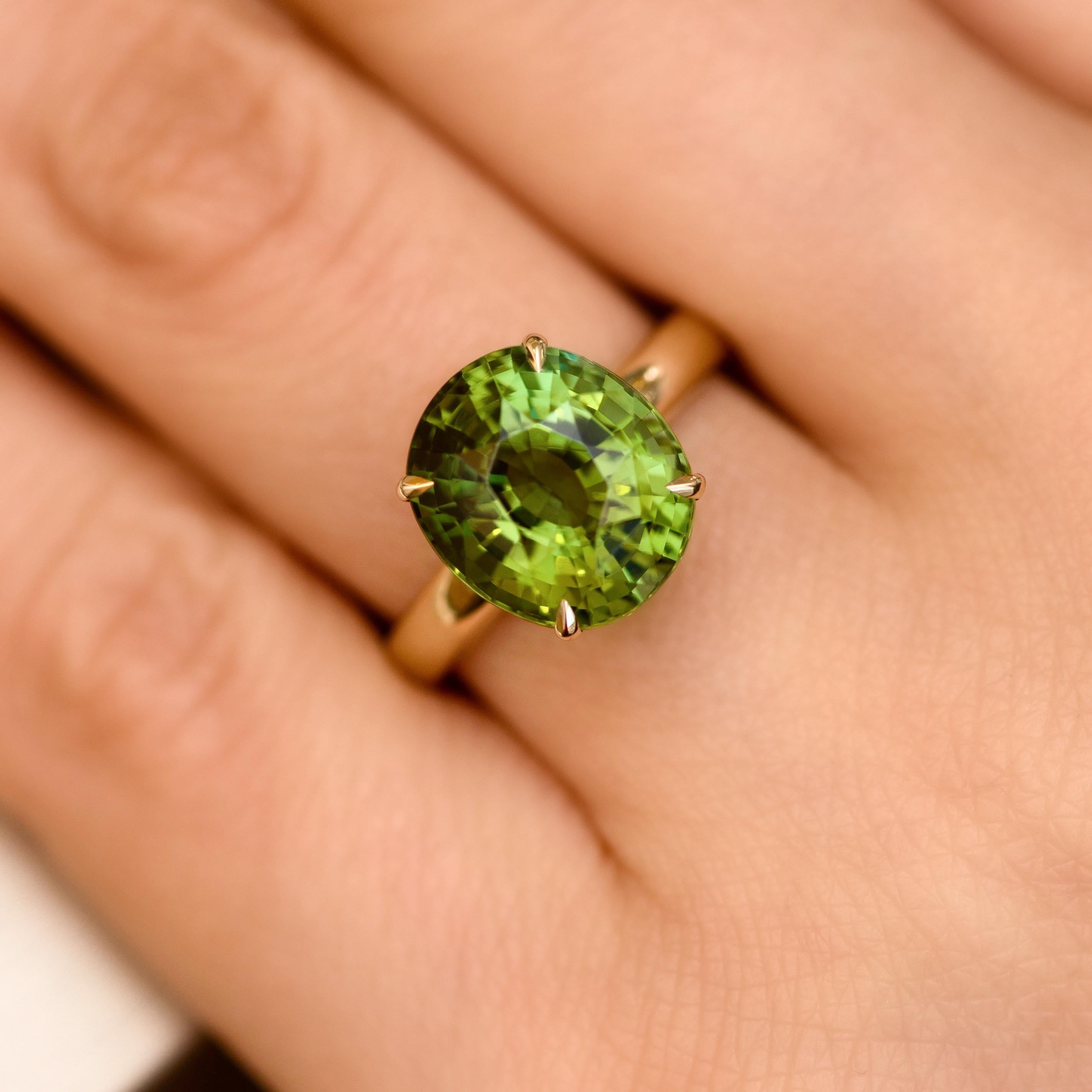 Green tourmaline - verdelite in a frame of yellow gold. 
Tourmalines usually have mix of different shades inside one stone. 
This one has severals shades of green color. 
Classical cut plus elegant ring is more than enough for such interesting