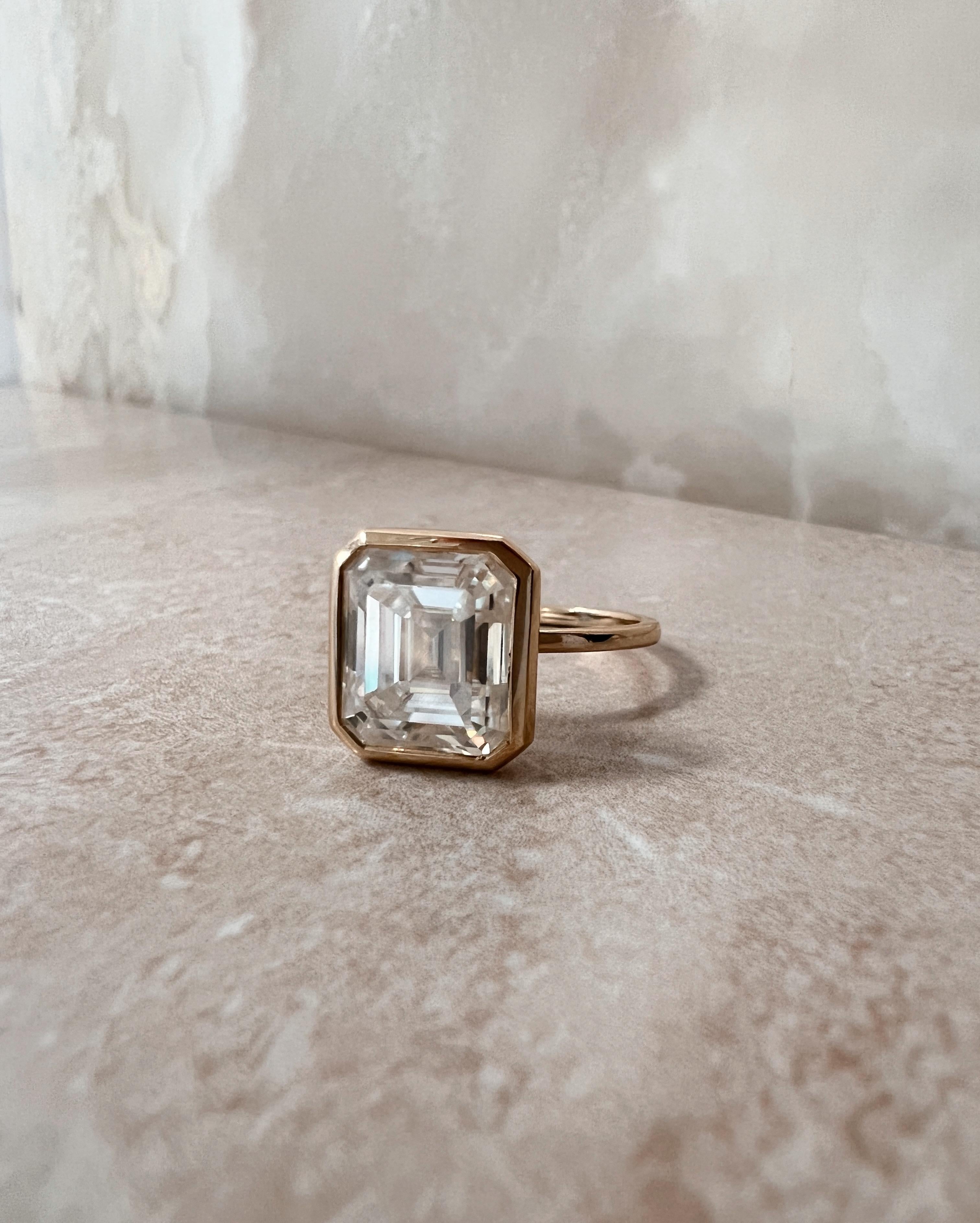 Classic Solitaire ring setting with bezel set center stone
Very simple metal band- approx. 1.25mm wide
Basket is set high
The ring pictured has a 3.70ct Emerald Cut Harro Gem Moissanite center stone (10x8mm, E/F)
14K Yellow Gold- Size 6
This item