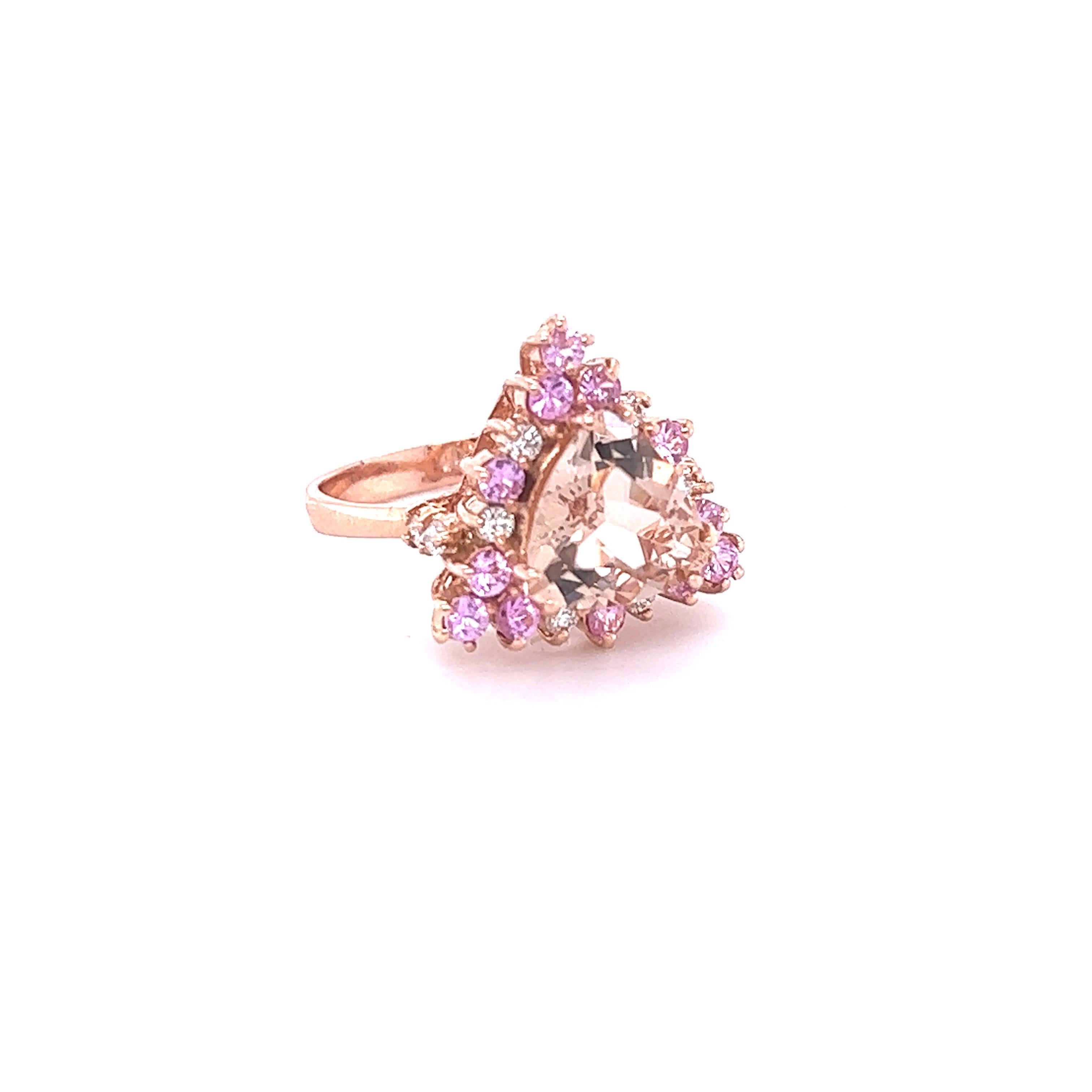 
This Morganite Diamond Ring has a 2.73 Carat Trillion Cut Peach Morganite and is surrounded by 12 Pink Sapphires that weigh 0.71 carats and 10 Round Cut Diamonds that weigh 0.26 carats (Clarity: VS, Color: H) The Total Carat Weight of the ring is