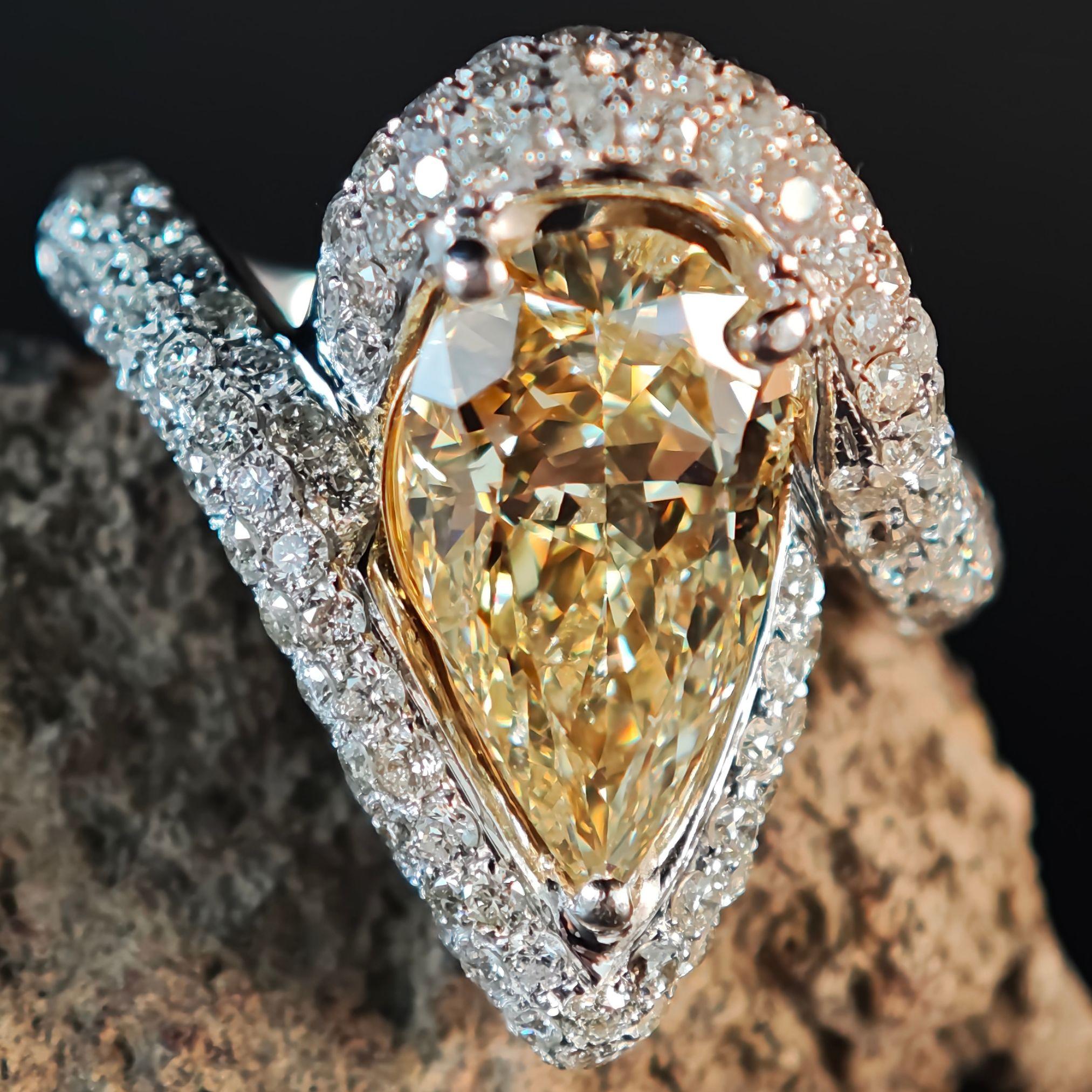 Este exquisito anillo de cóctel presenta un impresionante diamante natural certificado por el GIA en forma de pera de 3,70 quilates, con un raro color amarillo verdoso parduzco de fantasía, que irradia vivo fuego y brillo. La llamativa piedra