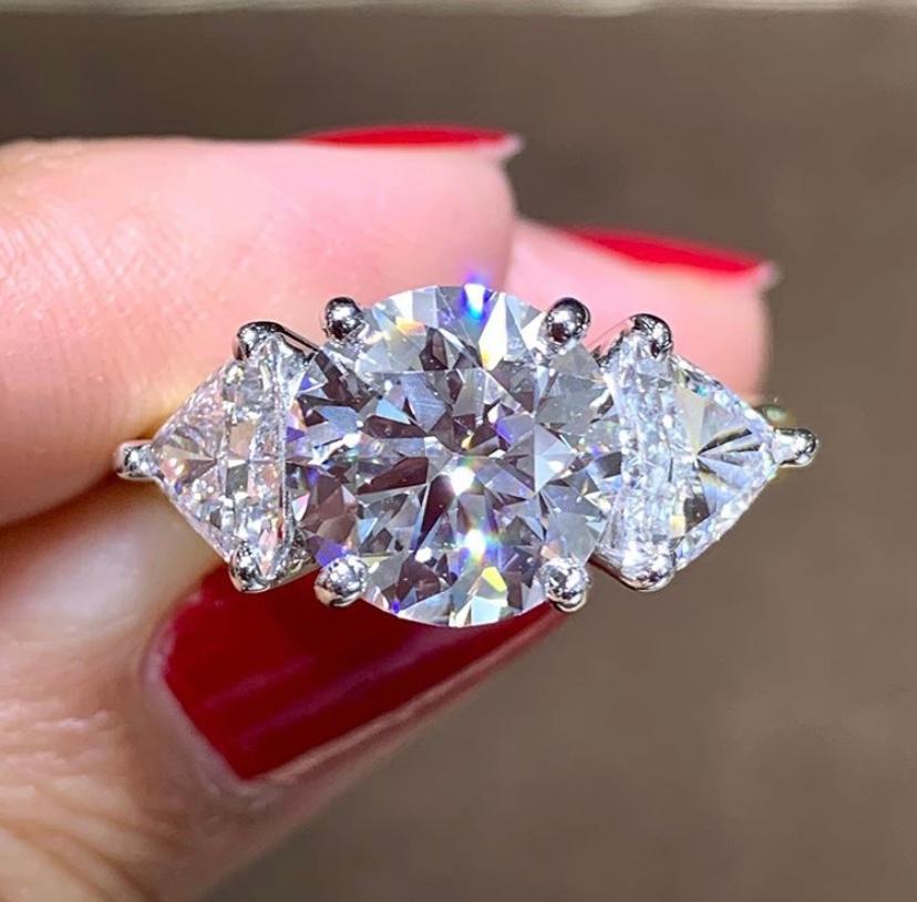 Platinum & 18kt yellow gold three stone diamond engagement ring in four prong style setting . Center Round Brilliant Cut diamond is of 3.70carats and is EGL certified D color VS1 Clarity, two side Trillion cut diamonds are of 1.60carats