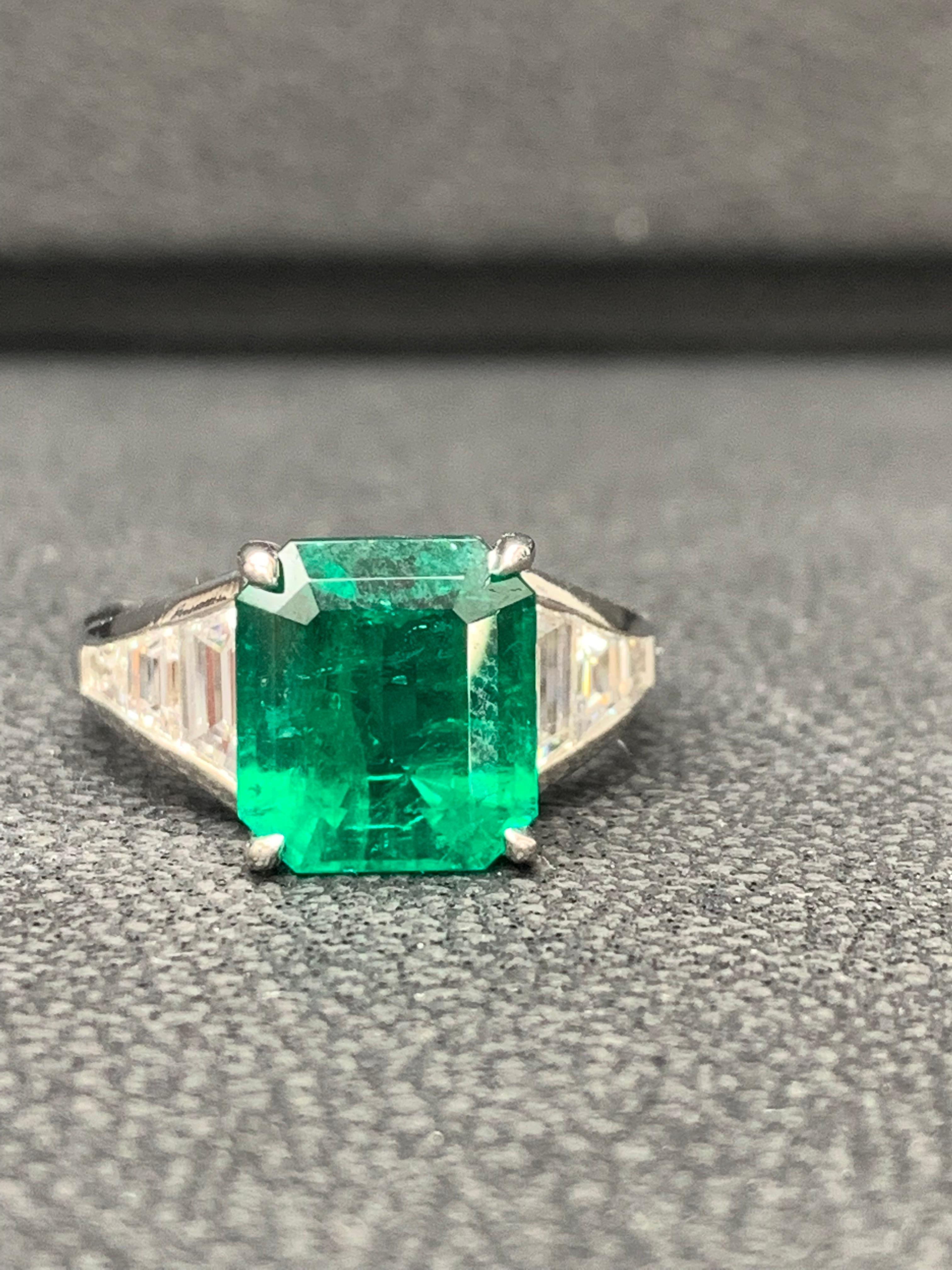 A stunning well-crafted engagement ring showcasing a 3.72-carat  emerald-cut Emerald. Flanking the center diamond are perfectly matched graduating trapezoid diamonds, channel set in a polished platinum mounting. 6 Accent diamonds weigh 1.05 carats