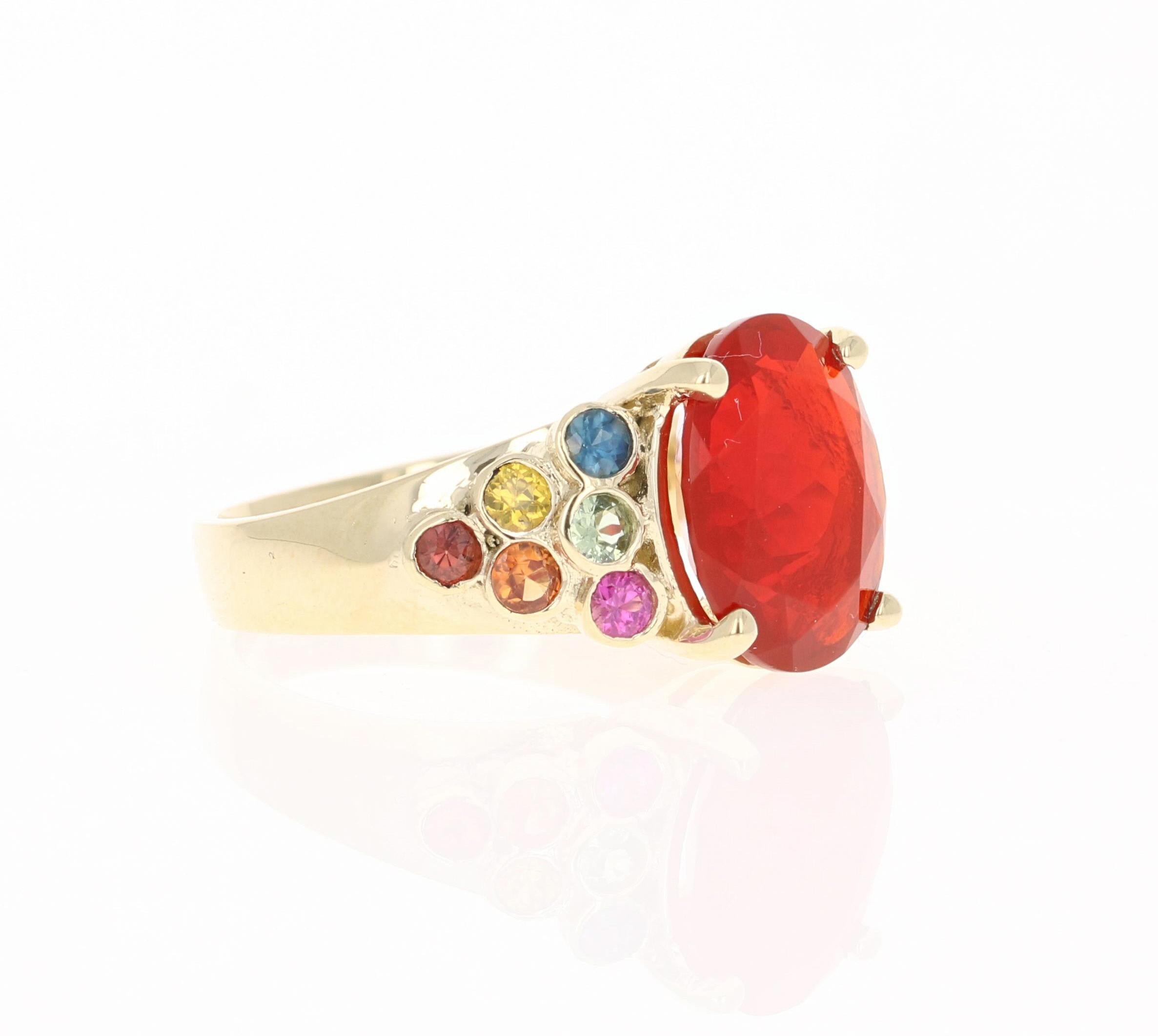 This ring has a 2.90 Carat Oval Cut Fire Opal as its center stone and is elegantly surrounded by 12 Round Cut Multi-Colored Sapphires that weigh 0.82 Carats. The measurements of the Fire Opal are 12 mm x 10 mm. 
The total carat weight of this ring