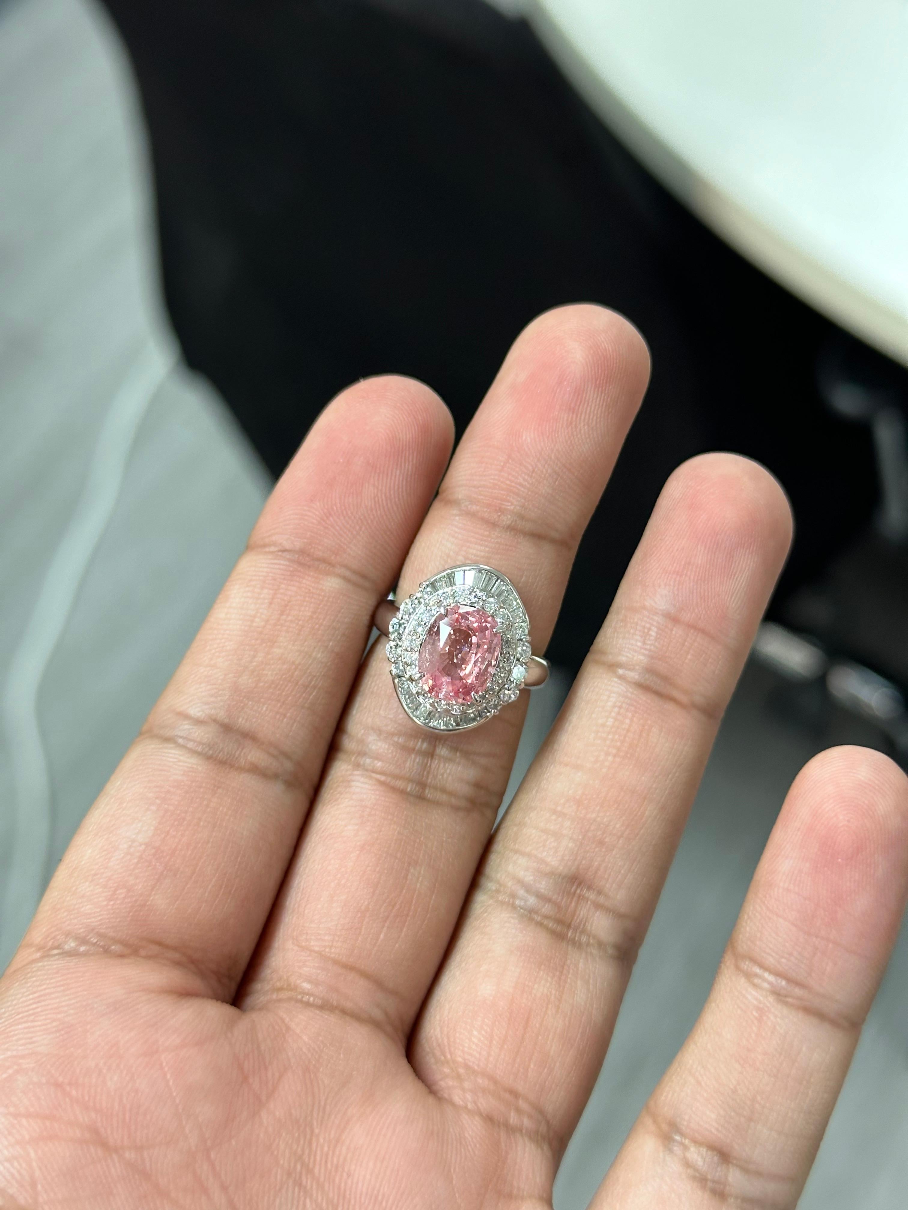 Prepare to be smitten by the sheer beauty of this absolutely fascinating Padparadscha Sapphire Ring. From the moment you lay your eyes on it, you'll fall head over heels in love. This oval-shaped Padparadscha Sapphire weighs an impressive 3.73