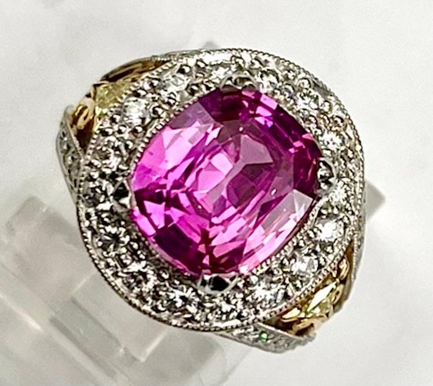 This beautiful, intricately designed ring features a richly hued 3.74Ct Cushion Cut Pink Sapphire accented by 2 Triangle Cut Natural Yellow Diamonds and a halo of natural white diamonds. The intensity of the pink color drives the desirability and