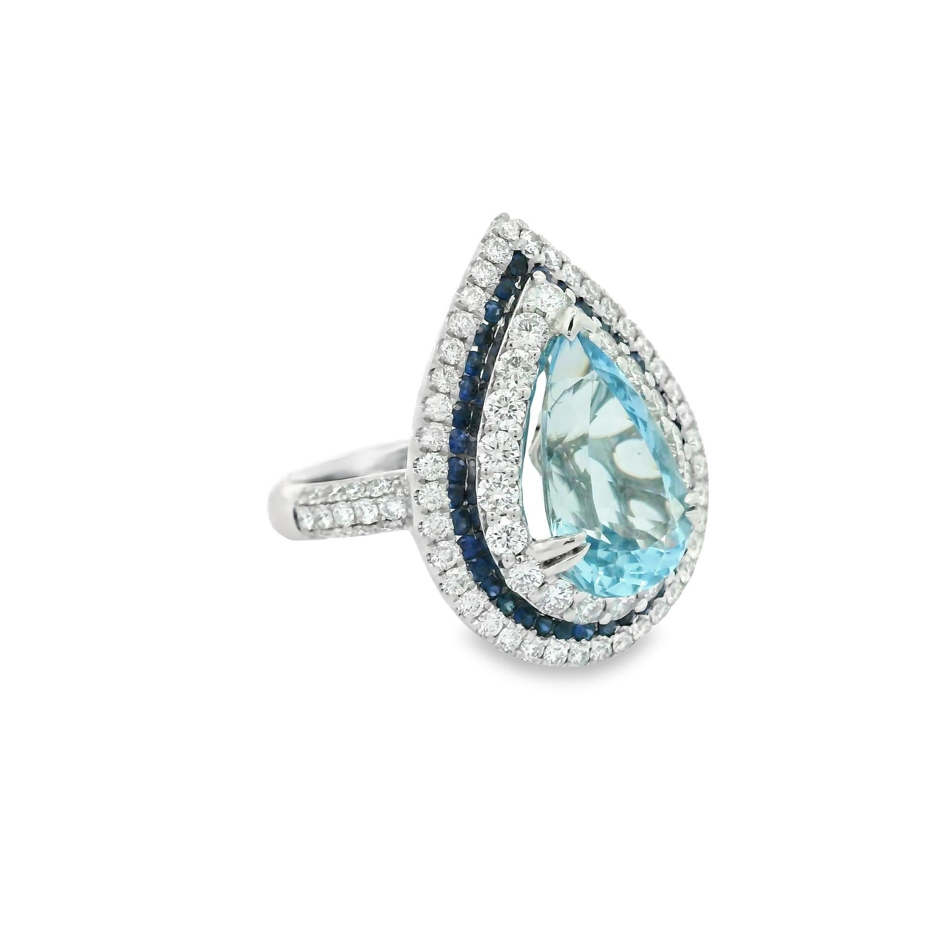 Un anillo fino y elegante con una aguamarina en forma de pera de 3,75 quilates de un intenso color azul marino. Está acentuado por un triple halo de diamantes redondos talla brillante y zafiros azules redondos. Los diamantes pesan un total de 1,42