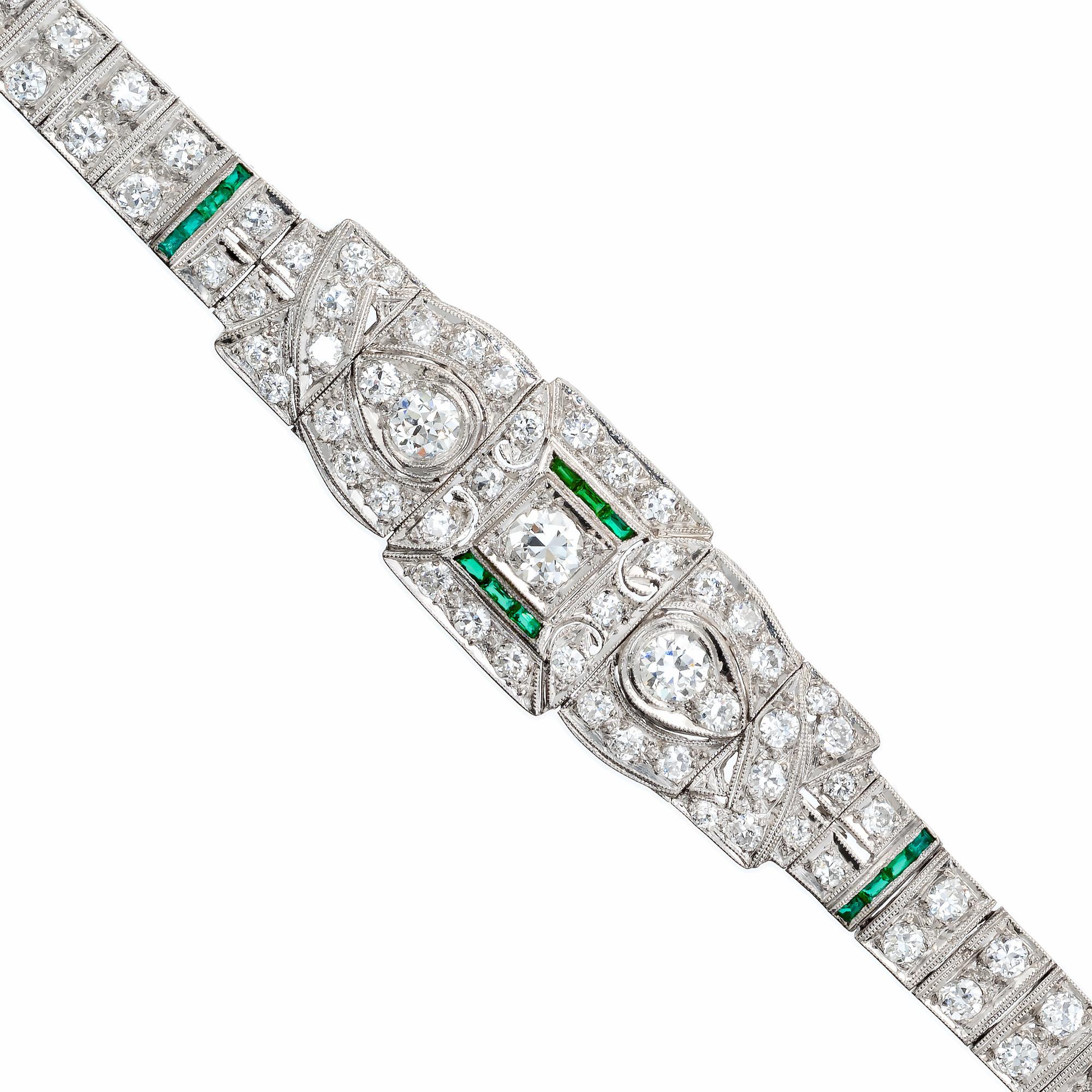 1920's Art Deco diamond and emerald bracelet. This exquisite Art Deco platinum bracelet boasts 3 old European cut diamonds with the center stone partly framed with a half halo of 14 French cut emeralds which are accented buy 98 round cut diamonds