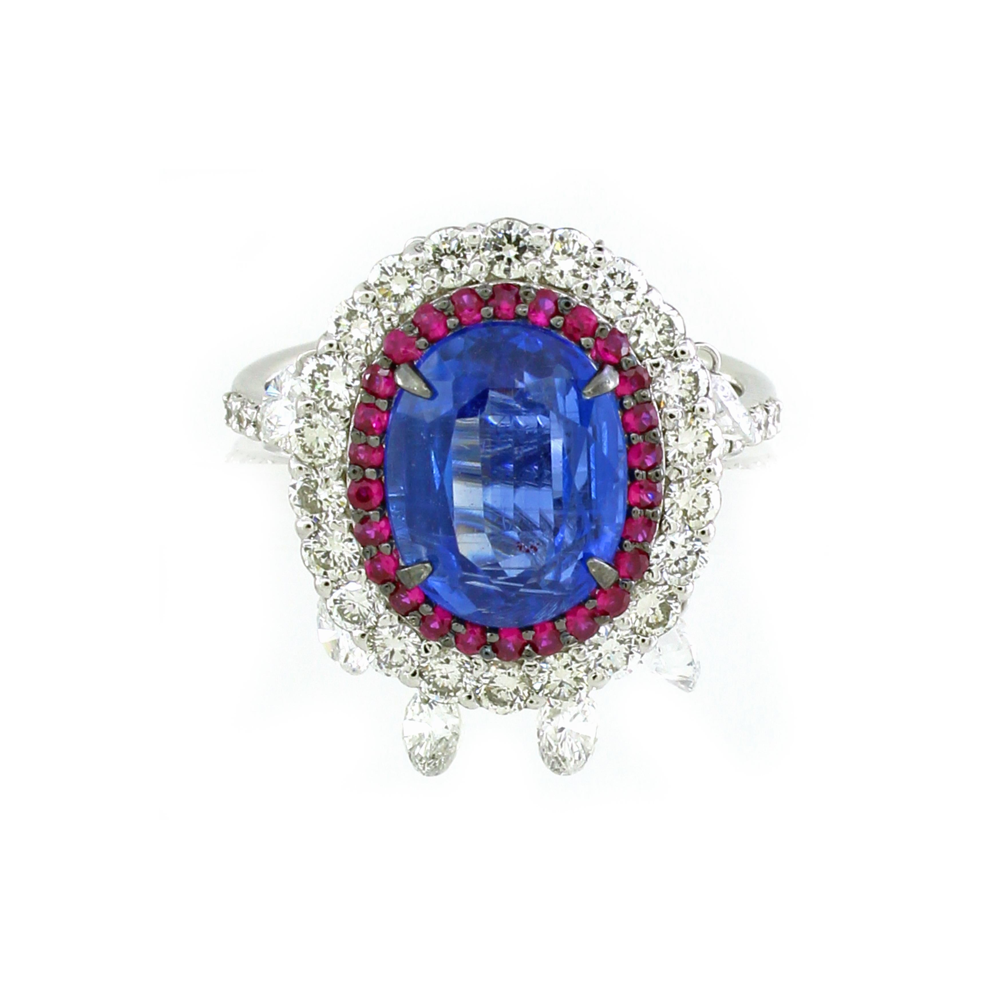 This exquisite cocktail ring features a stunning 3.53-carat oval kyanite at its center, exuding a deep, captivating blue. The kyanite is surrounded by two halos that elevate its brilliance: the first halo consists of 26 small round rubies totaling