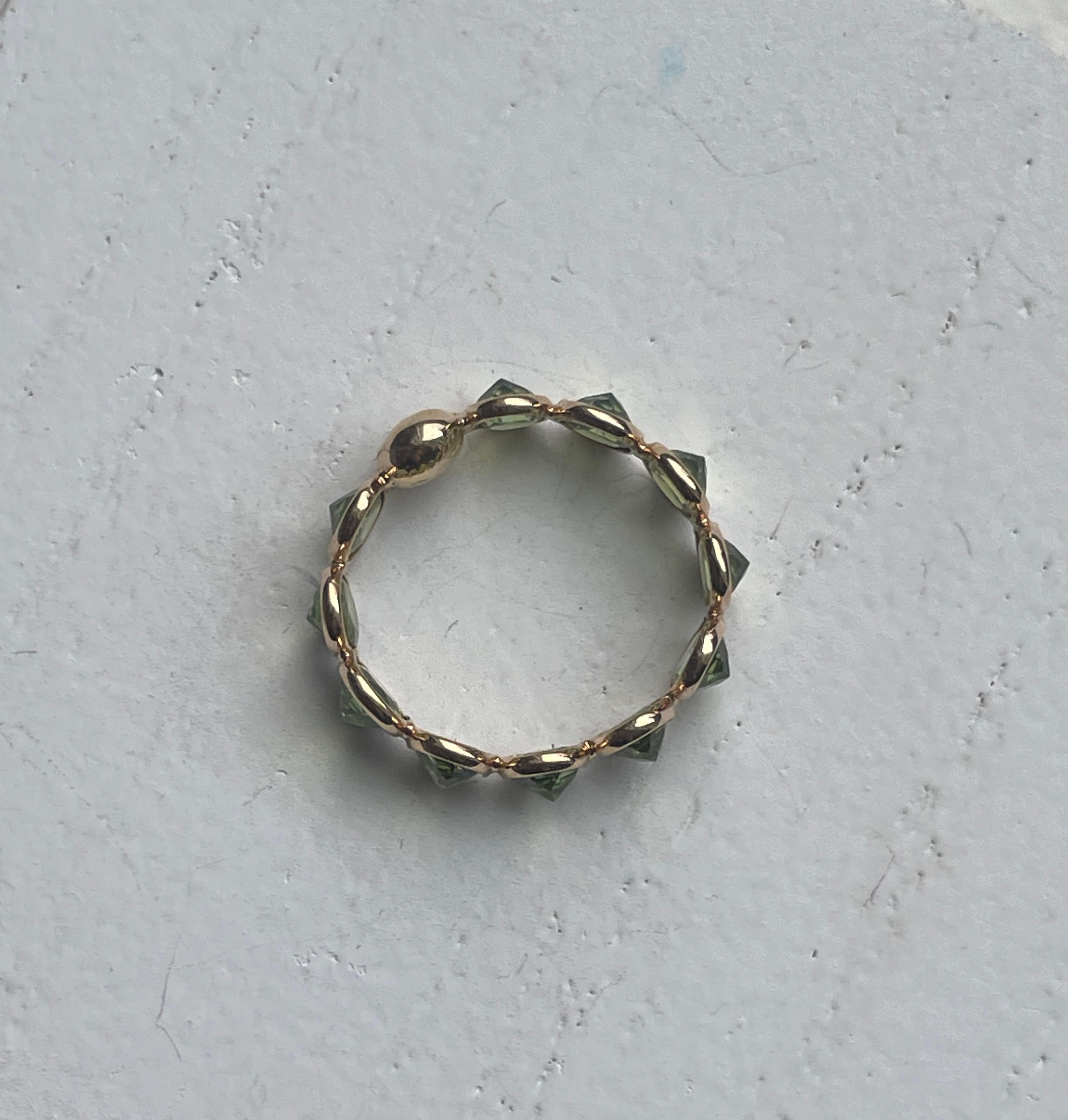 This 18K Gold eternity band is comprised of 11 Peridot Ovals that are checkered cut and set upsize down in a bezel setting. The setting of this ring is truly unique, it allows for the point or the underside of the stone to sit at the surface
