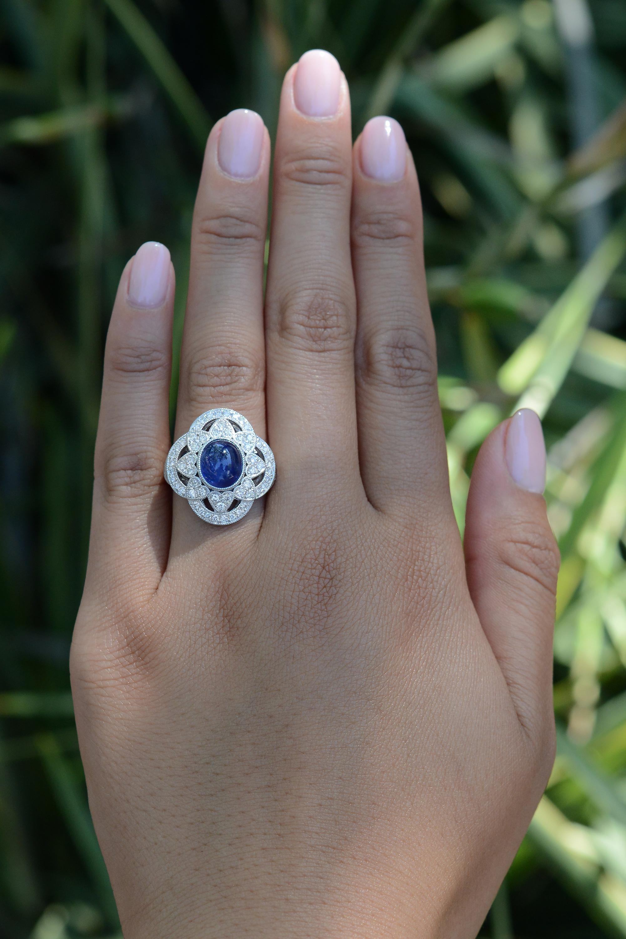 A tasteful right-hand cocktail ring with the perfect amount of flair and finger coverage. The cabochon cut sapphire is a silky blue color with even color and deep saturation throughout. Surrounding the 3.79 carat gem, a halo of platinum hearts with