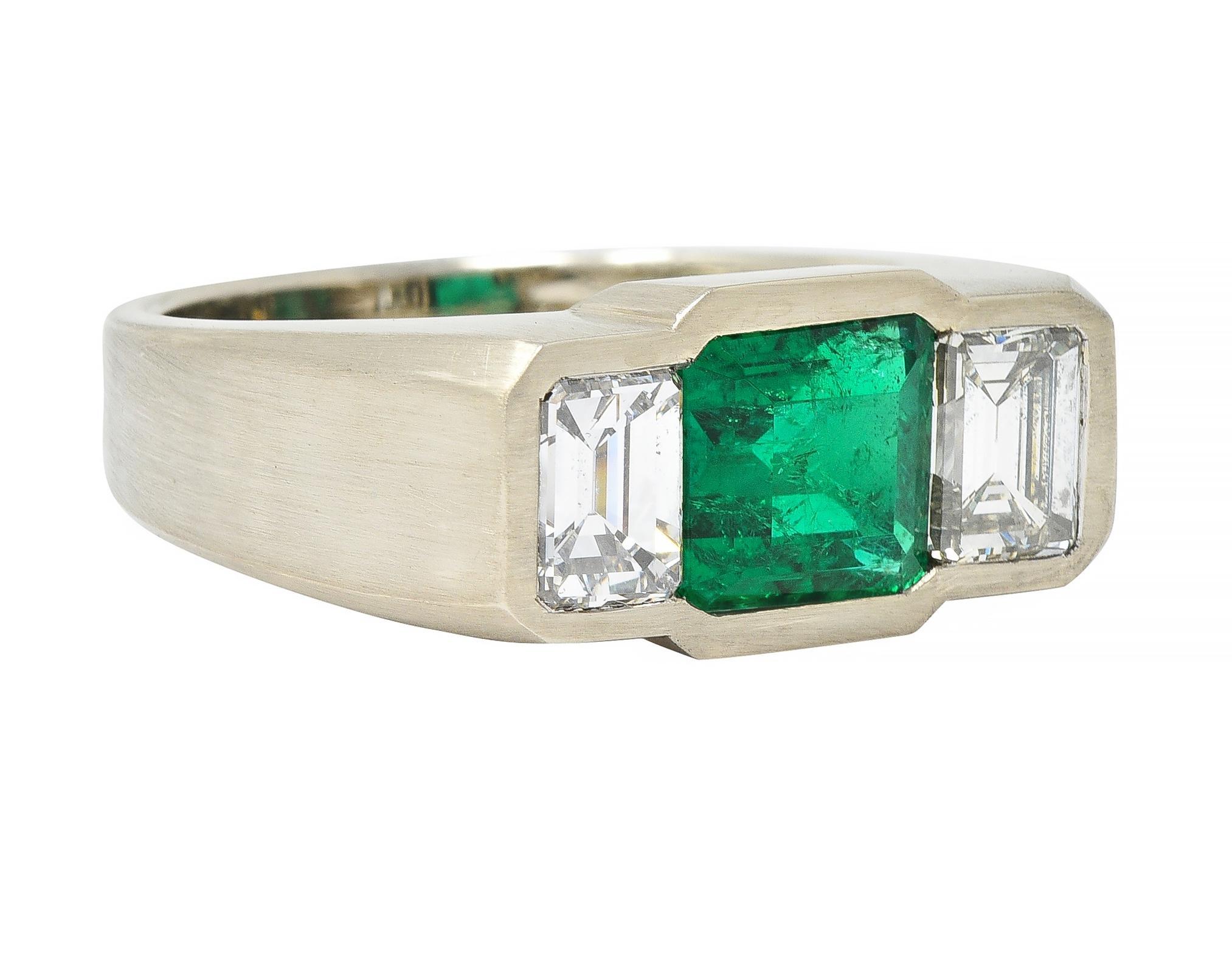 Centering an emerald cut emerald weighing 2.05 carats total - transparent medium green
Natural Colombian in origin with minor traditional clarity treatment 
Flush set and flanked by emerald cut diamonds 
Weighing approximately 1.74 carats total 
H