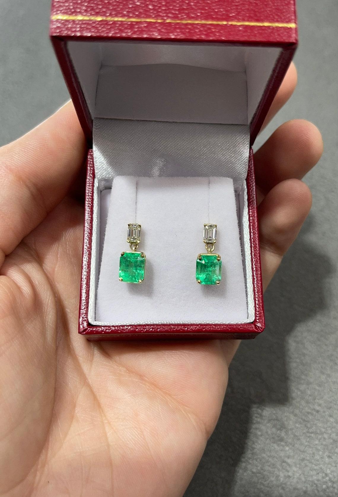 Ausgestellt ist ein atemberaubendes Paar Ohrringe mit Smaragd und Diamanten, baumelnd. Zwei wunderschöne kolumbianische Smaragde im Smaragdschliff mit einem Gesamtgewicht von 3,15 Karat, akzentuiert von zwei Diamantbaguetten. Die Smaragde und