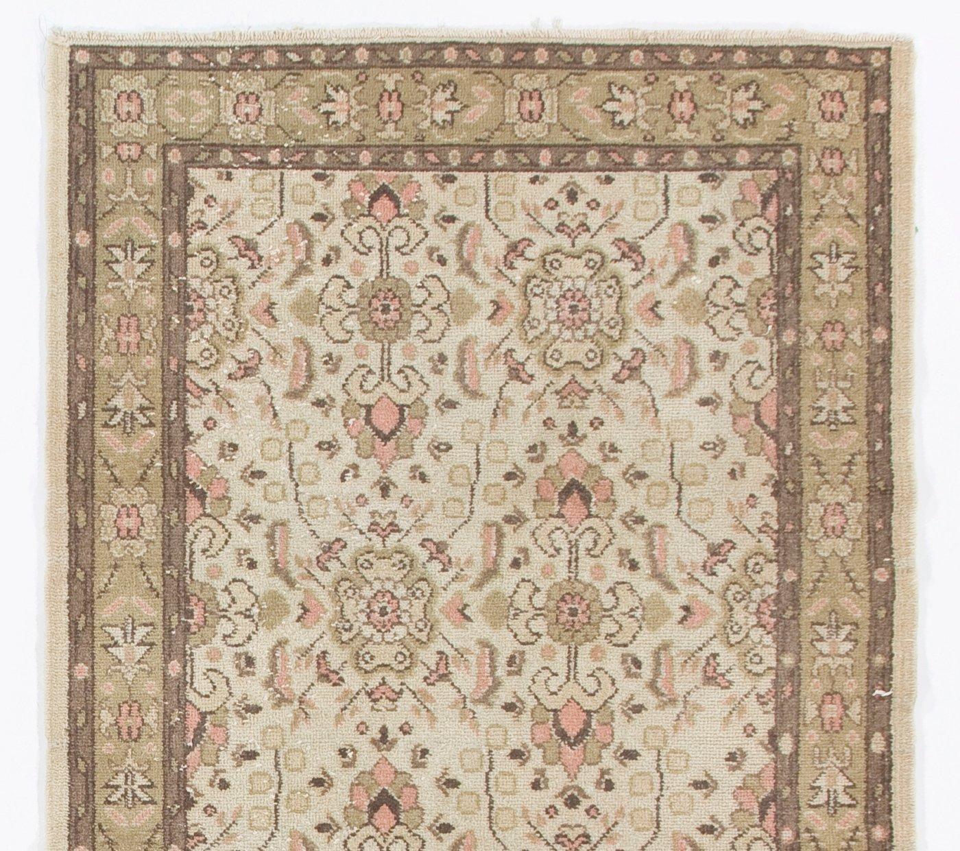 A vintage hand-knotted Turkish rug with an all-over floral design in coral pink and light moss green against a beige background. The rug is finely hand-knotted with even medium wool pile on cotton foundation. It is in very good condition, sturdy and