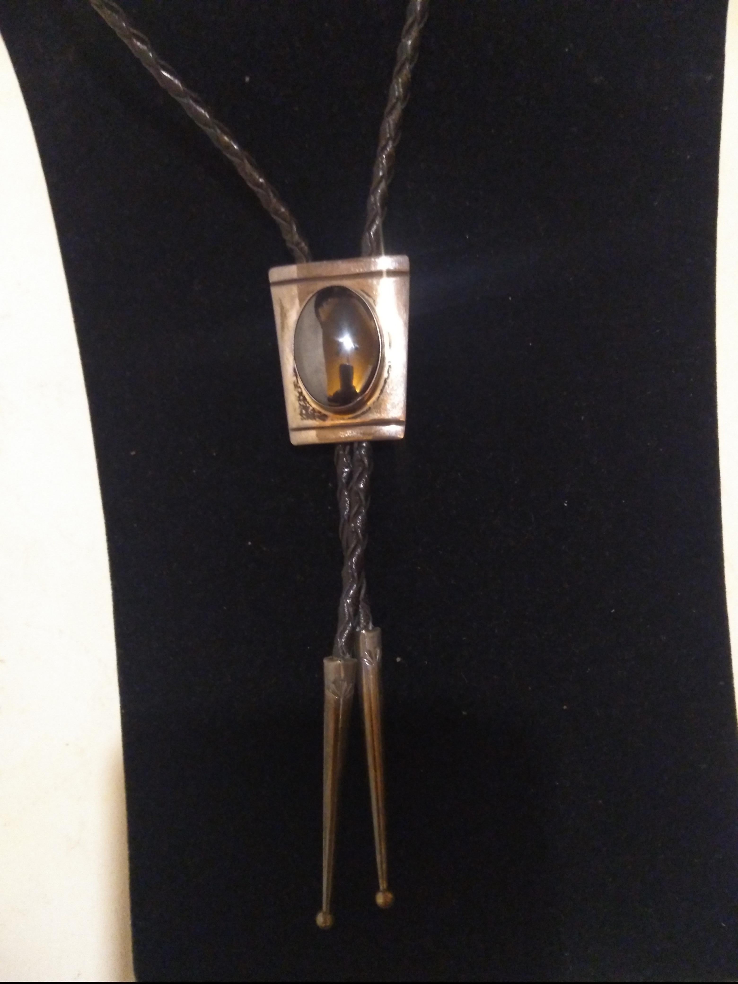 This is a beautiful bolo tie. It's made of braided leather and sterling silver and has an oval onyx setting in the medallion.. The medallion is rectangular. The tips are crafted in silver also.

Great for a night out on the town.


Ready to wear.
