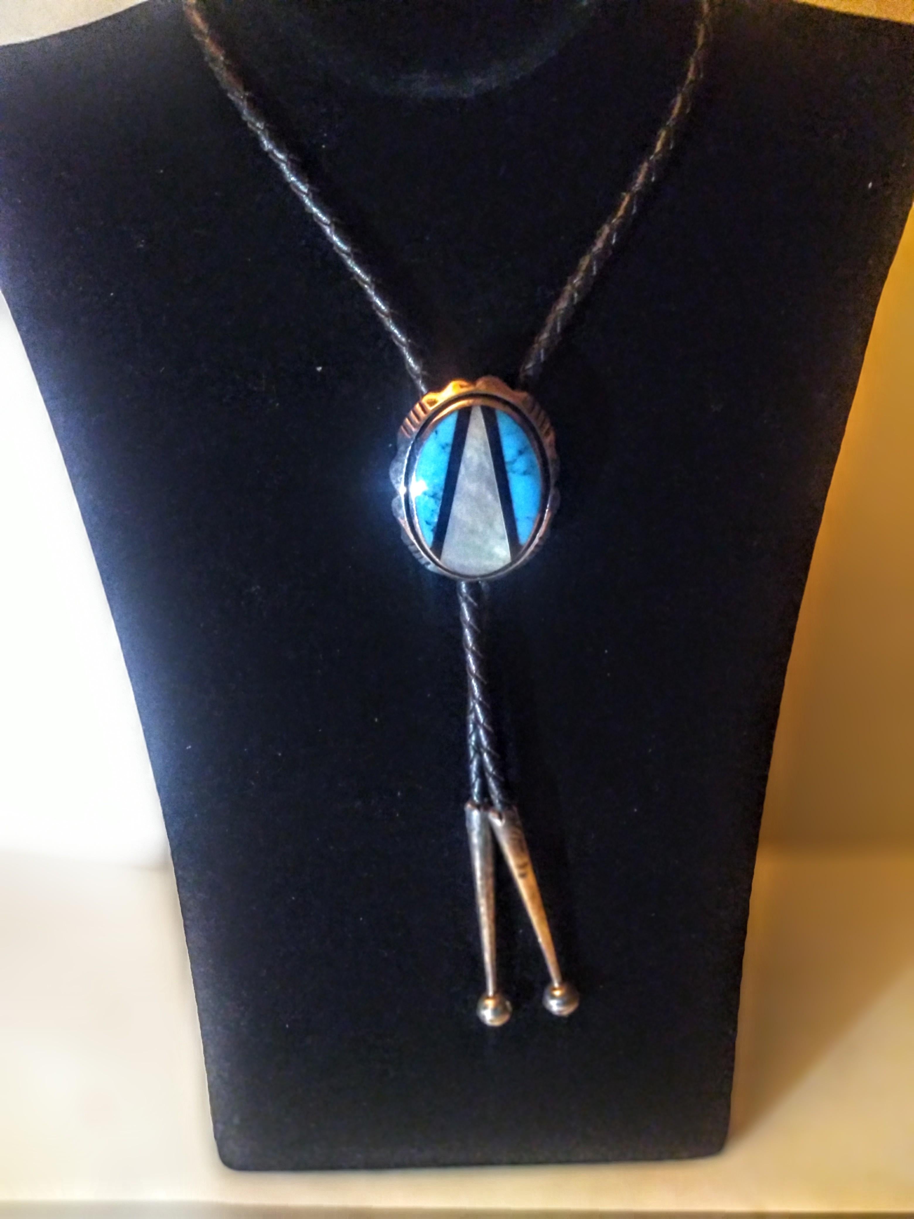 This is a beautiful bolo tie. It's made of braided leather and sterling silver with s turquoise and abalone setting in the medallion.. The abalone is shaped like an arrowhead piercing the turquoise.. The tips are crafted in silver also.

Great for a