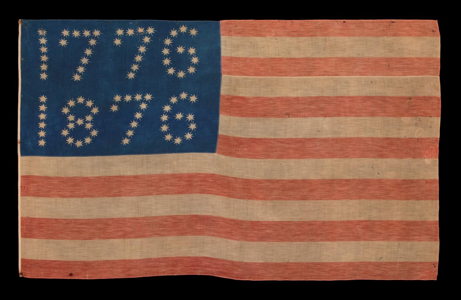 ANTIQUE AMERICAN FLAG WITH 10-POINTED STARS THAT SPELL “1776 – 1876”, MADE FOR THE 100-YEAR ANNIVERSARY OF AMERICAN INDEPENDENCE, ONE OF THE MOST GRAPHIC OF ALL EARLY EXAMPLES 

Many fantastic star patterns were made in the patriotism that