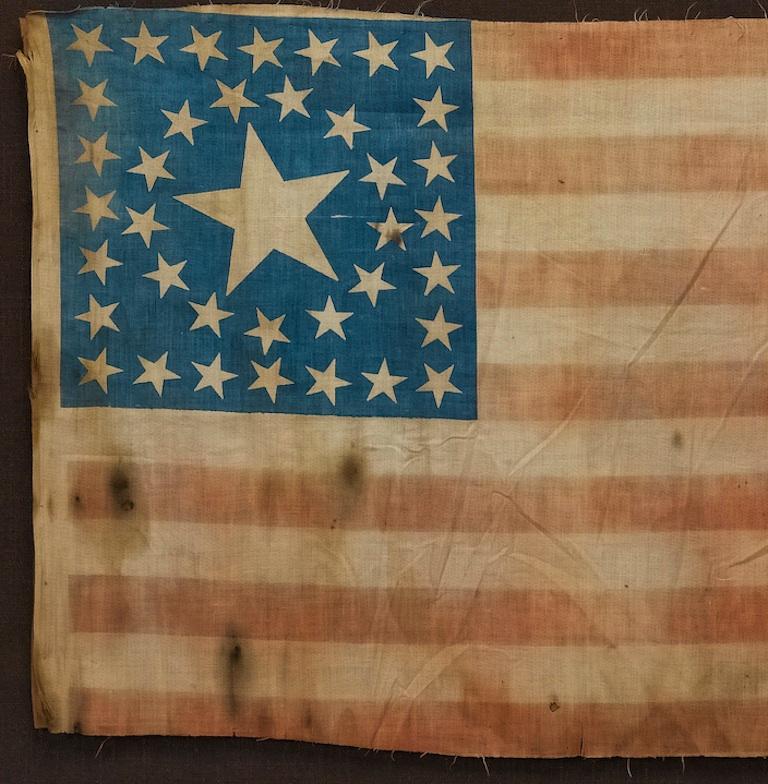 Dies ist eine auffällige amerikanische Flagge mit 38 Sternen. Die Flagge stammt aus den Jahren 1876-1890, als Colorado (dargestellt durch den großen Stern in der Mitte des Kantons der Flagge) als 38. Staat der Union beitrat. Diese Flagge, die die