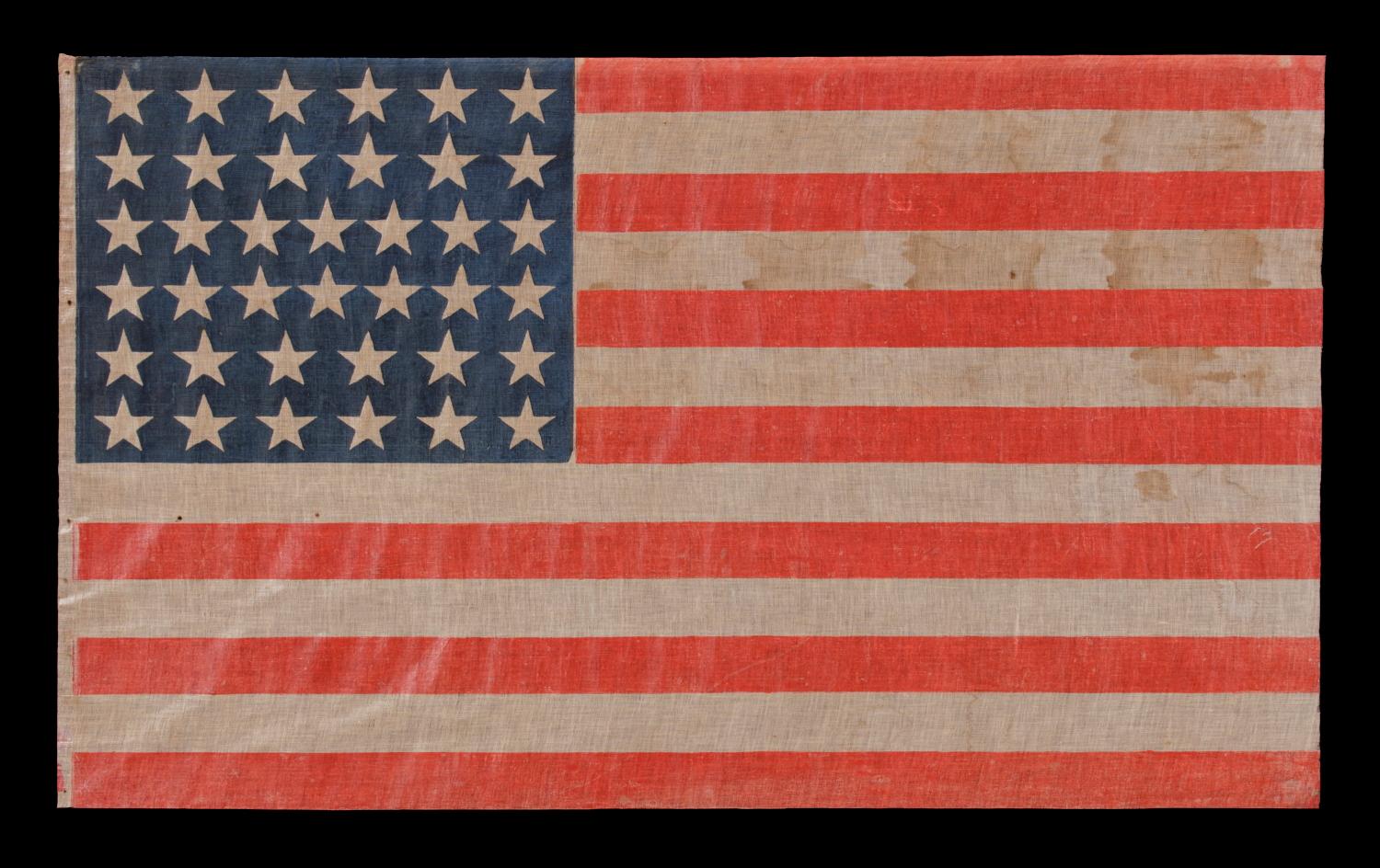 38 STAR ANTIQUE AMERICAN PARADE FLAG, IN AN ESPECIALLY LARGE SCALE AND WITH BOLD COLOR, MADE DURING THE PERIOD WHEN COLORADO WAS THE MOST RECENT STATE ADDED TO THE UNION, 1876-1889 

38 star American national parade flag, printed on coarse cotton.