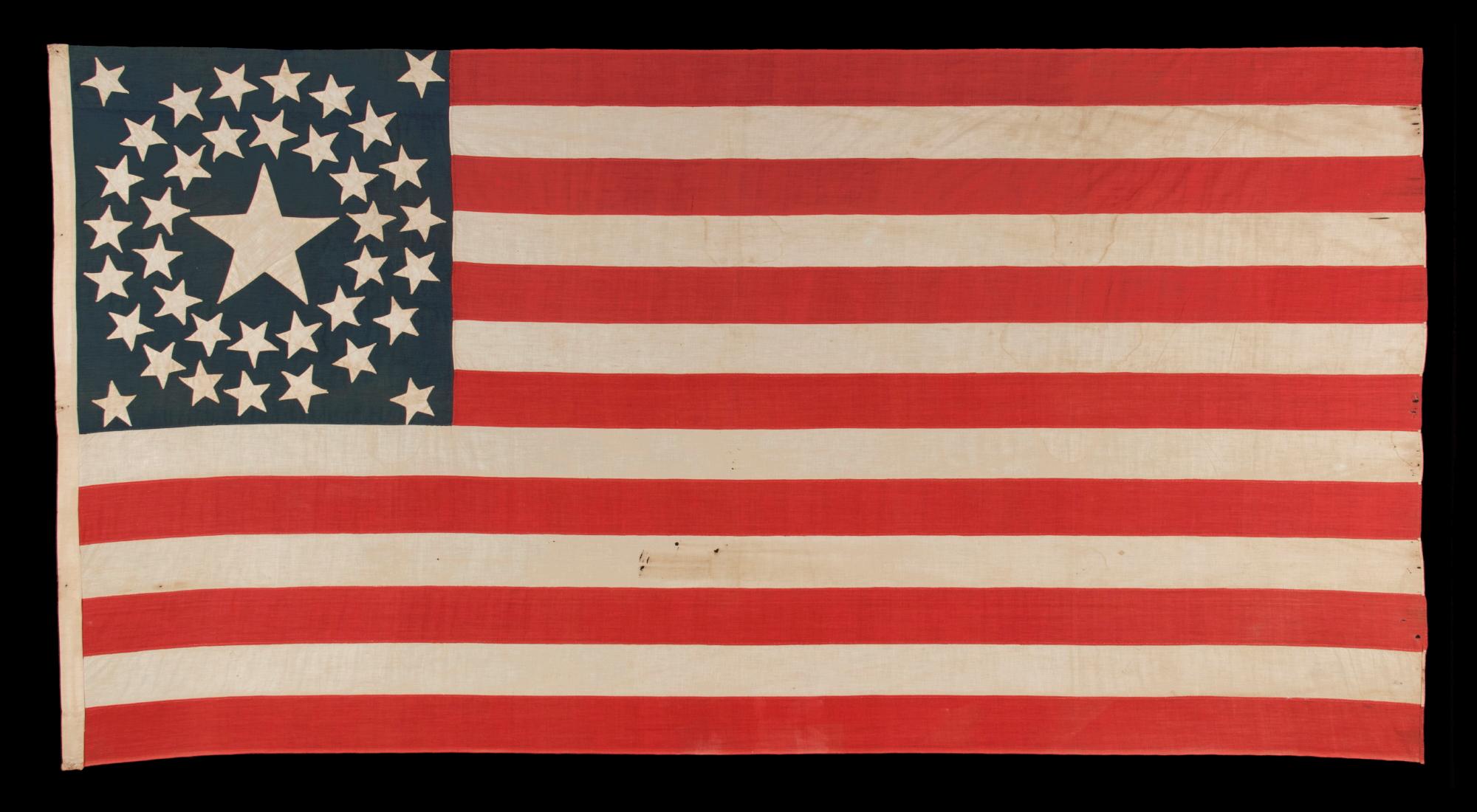 38 STAR ANTIQUE AMERICAN FLAG WITH A DOUBLE-WREATH CONFIGURATION THAT FEATURES AN ENORMOUS CENTER STAR, REFLECTS THE PERIOD OF COLORADO STATEHOOD, 1876-1889:

38 star American national flag, made entirely of plain weave cotton. The stars are
