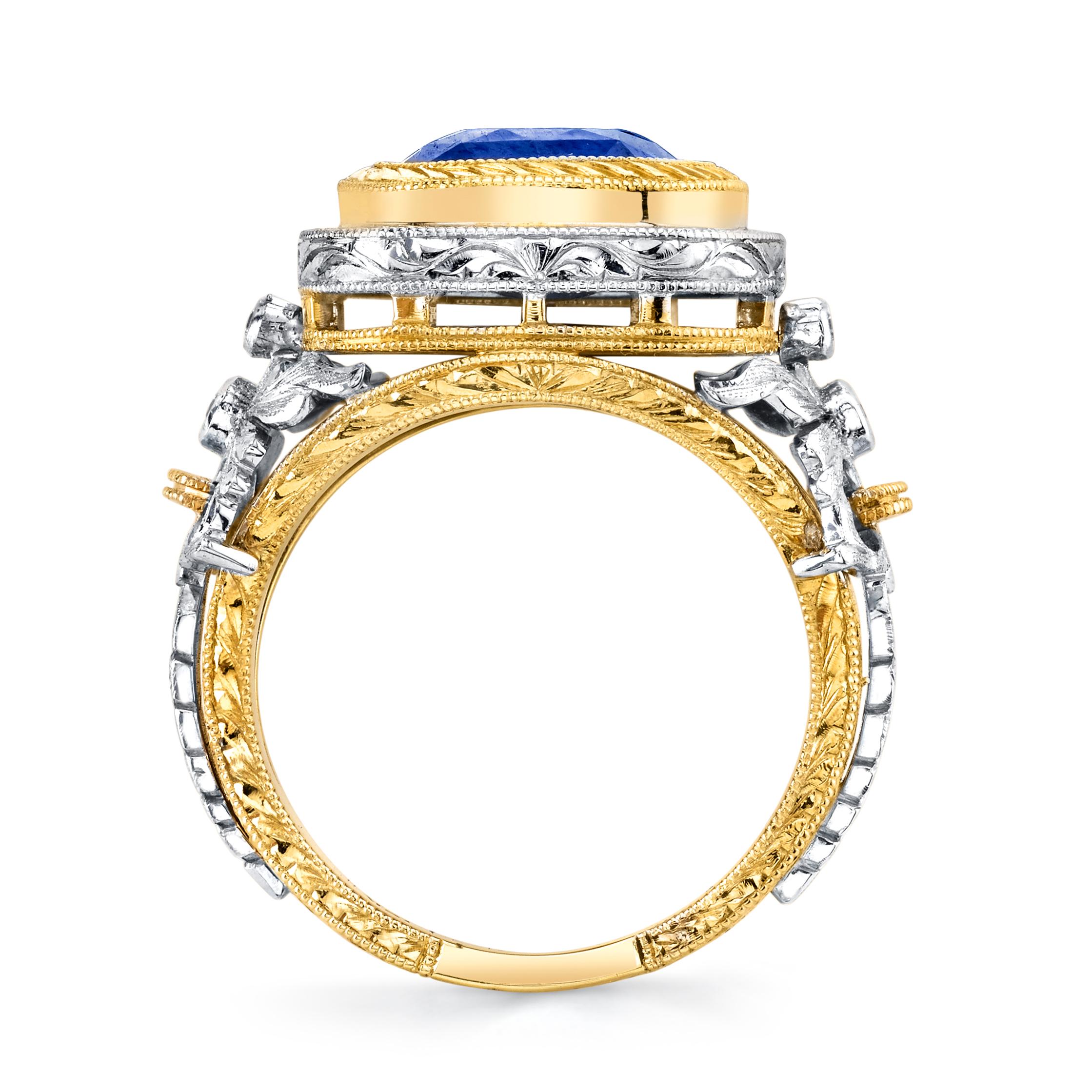 Dieser wunderschöne Ring ist ein atemberaubendes Kunstwerk mit einem leuchtenden, kissenförmigen blauen Saphir, der in einem handgravierten Ring aus 18 Karat Gelbgold 
