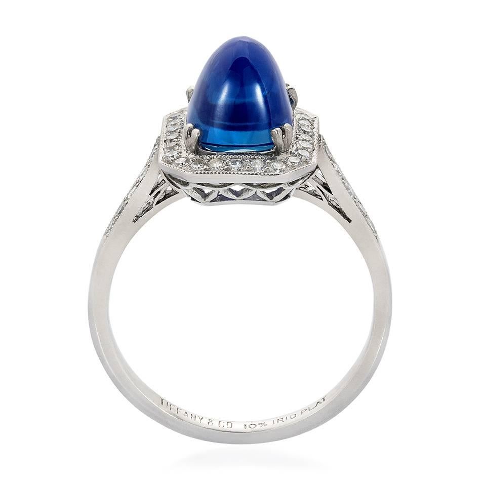 A 3.80 ct sugarloaf Kashmir sapphire and diamond Art Deco ring by Tiffany & Co. The no heat Kashmir sugarloaf sapphire set within a single cut diamond border to single cut diamond shoulders and an openwork  lattice gallery, set in iridium platinum.