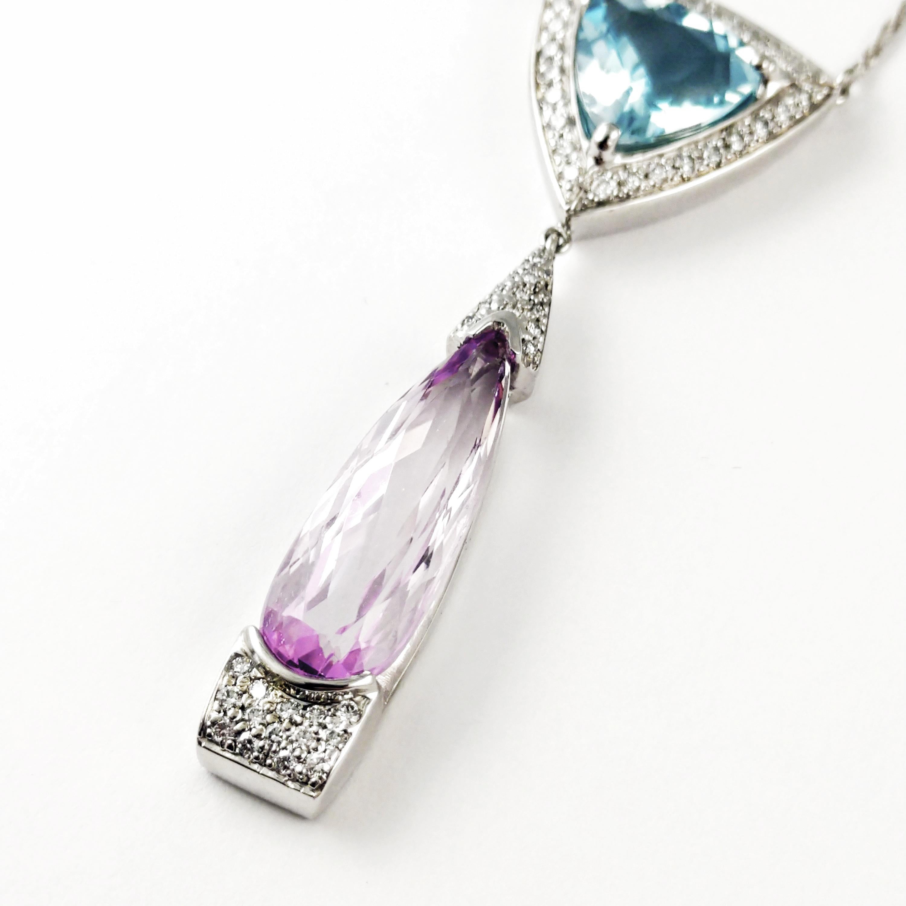 This elegant ladies 14KT white gold drop necklace is featuring a 3.80 ct. trillion-cut aquamarine that is prong set into a diamond halo basket. Also, dangling below that is an 8.20 ct. pear-shape kunzite that is exhibiting beautiful pink tones to