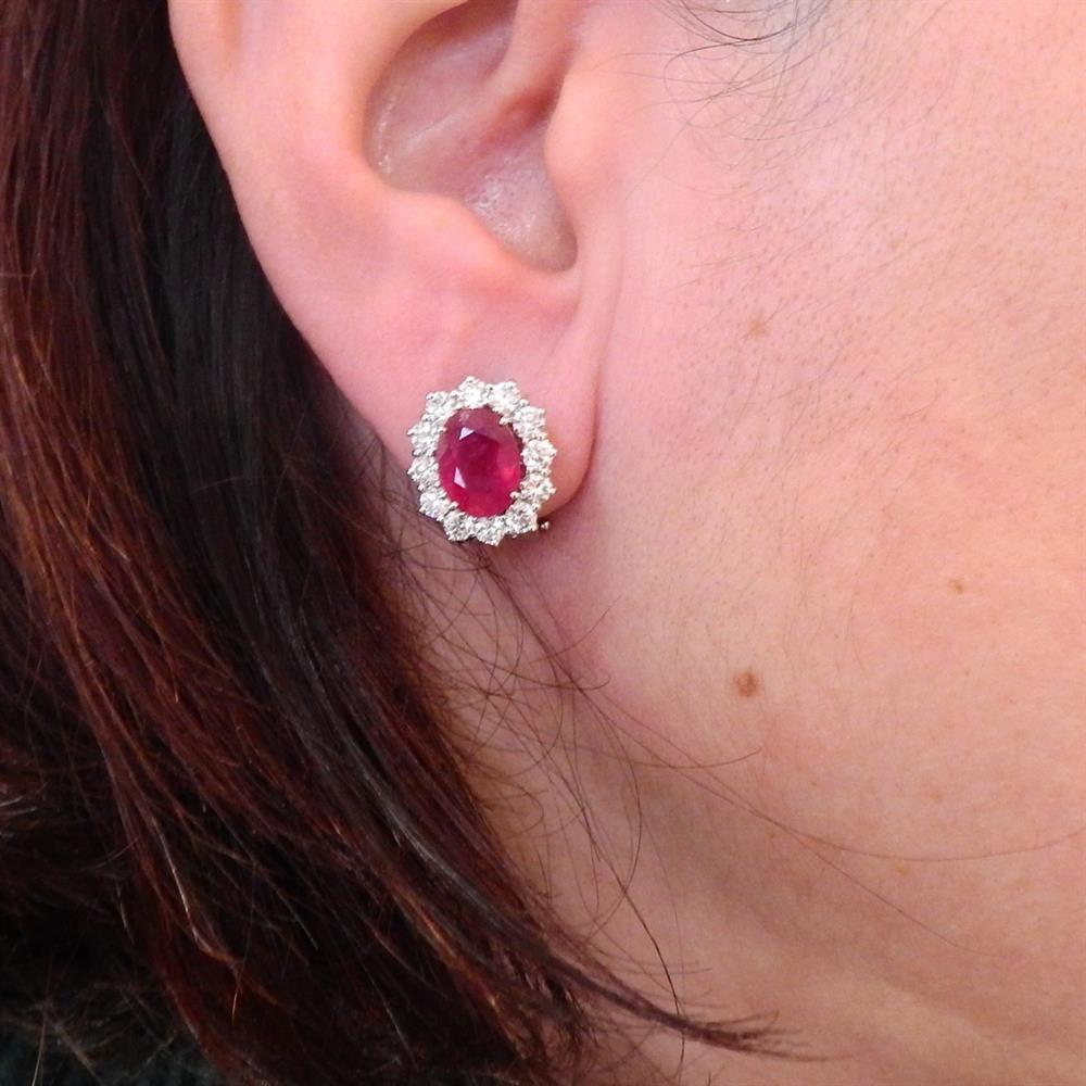 Pair of 18k white gold oval earrings, set with two rubies, approx. 3.80ctw, surrounded with approx. 1.70ctw in diamonds. Earrings are 15mm x 14mm. Weigh 8.3 grams.