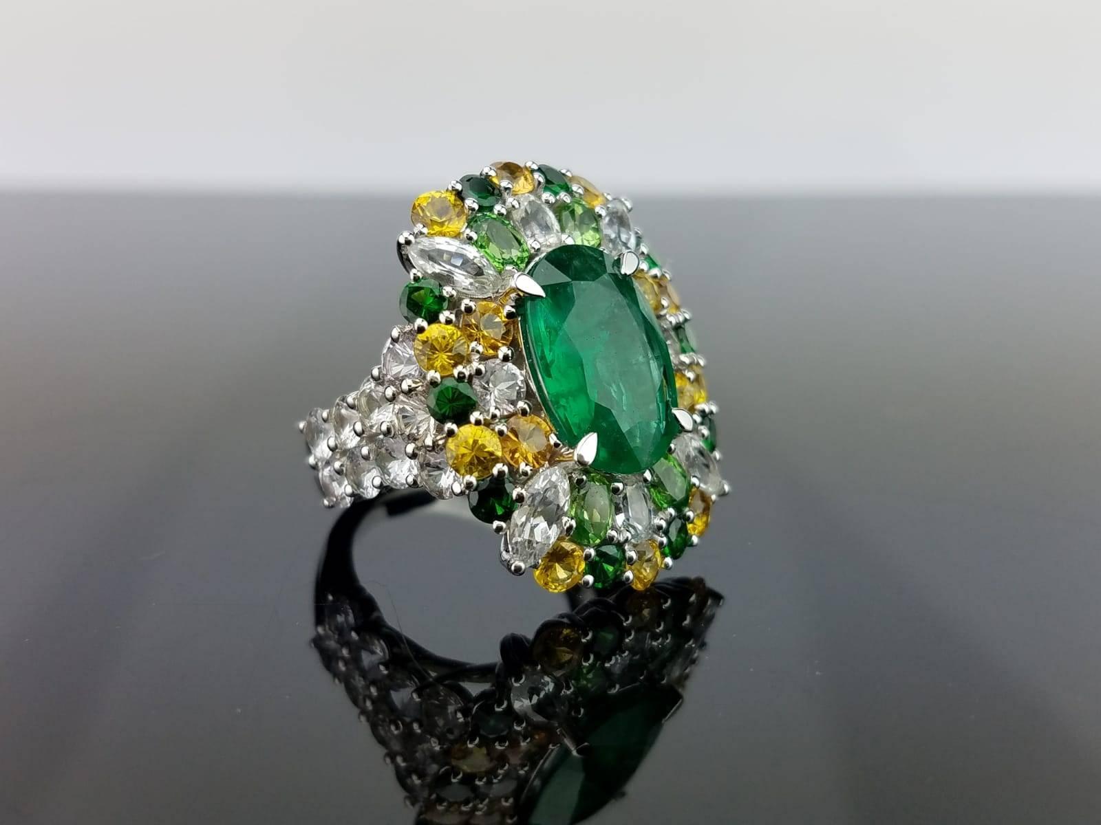 An eye-catching cocktail ring with a 3.81 carat oval shape Zambian Emerald (looks like 5 carat) sorrounded with 6.83 carats of colored Sapphire and 1.86 carats of Green Garnet. All set in 18K Gold weighing 12.50 grams. 

Currently a ring size US 6,