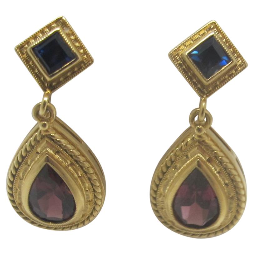 These beautiful earrings were handmade by one of our Master Jewelers in Los Angeles. They feature pear shaped raspberry colored tourmalines and princess cut navy blue sapphires. These one-of-a-kind earrings are a beautiful and unusual pairing of