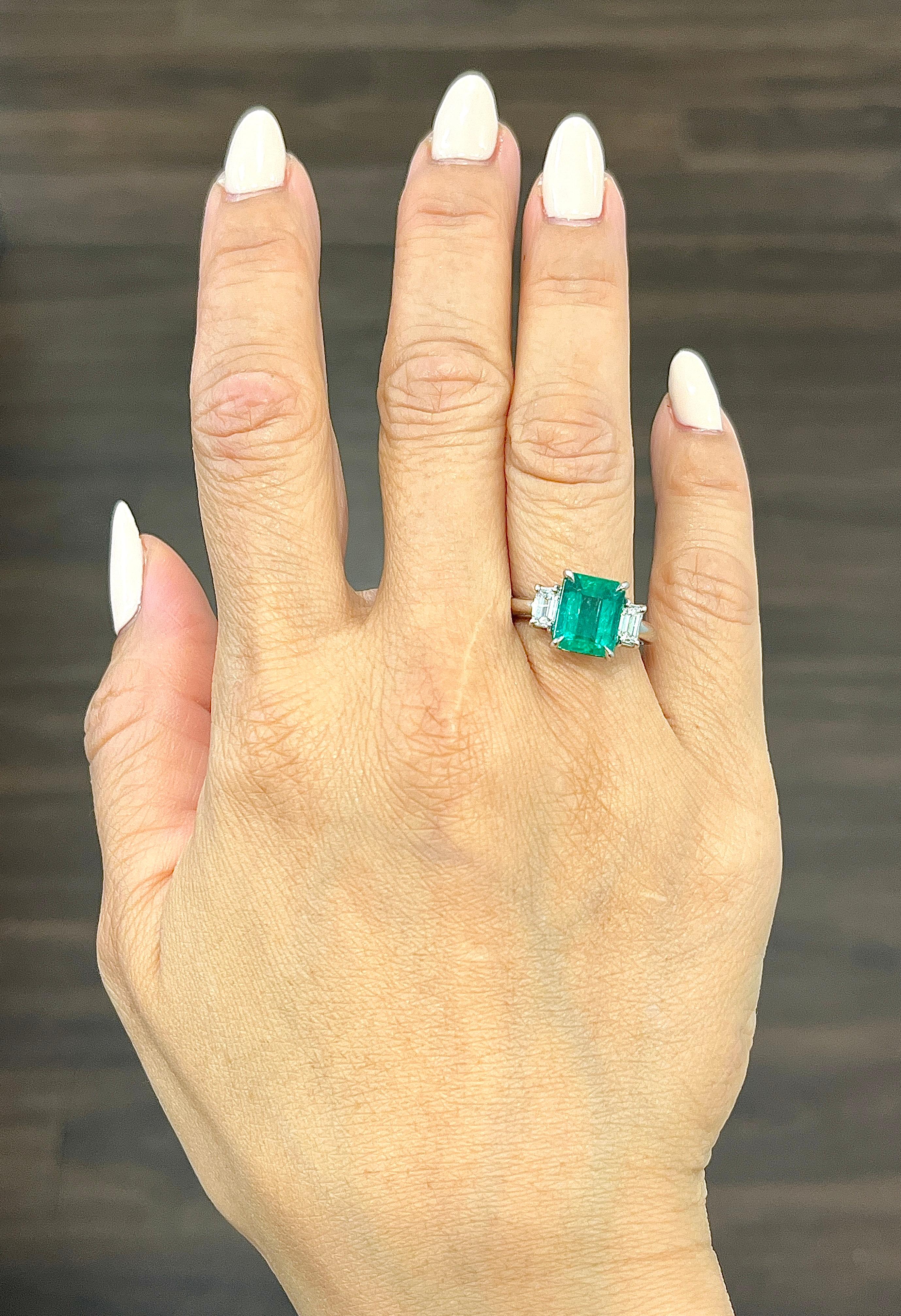This gorgeous natural emerald and diamond ring is sure to turn heads. The 3.28 ct natural emerald is encased in platinum and sits right in the center of the ring. The two emerald cut diamonds weighing 0.55 ct hug the center stone. The diamonds have