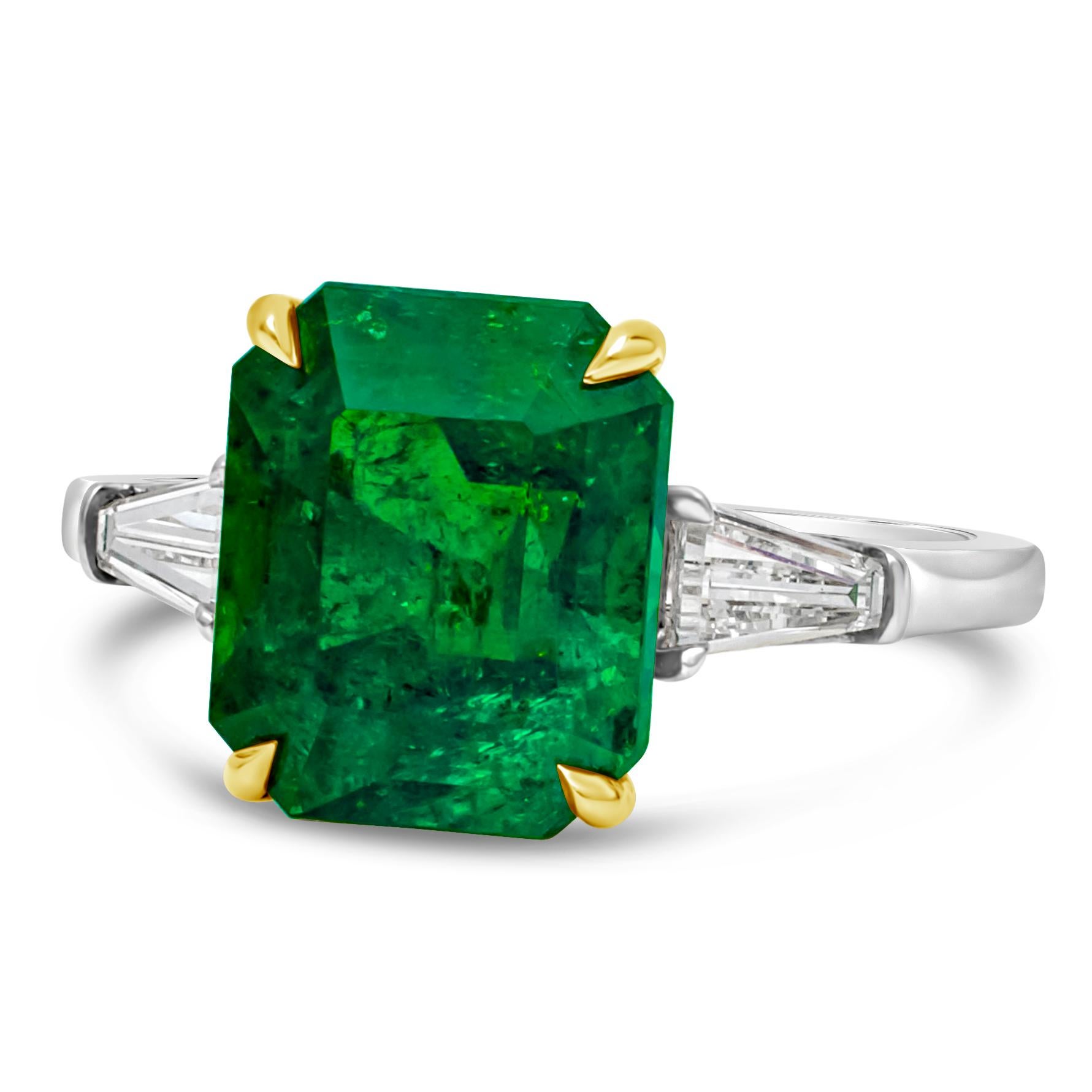 A beautiful and elegant engagement ring, showcasing a color-rich emerald cut green emerald weighing 3.84 carats. Flanked by two baguette cut diamonds weighing 0.40 carats total and set on a polished 18K yellow gold and platinum. Size 6 US, resizable