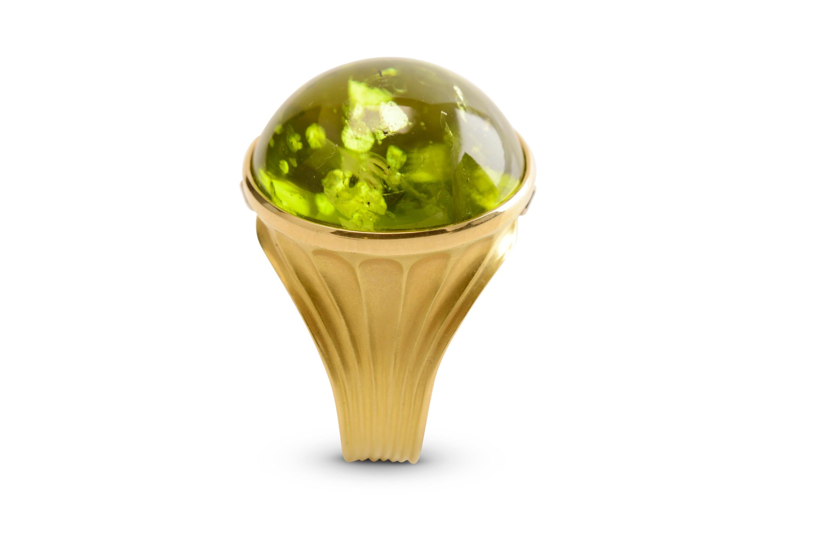 A magnificent peridot cabochon of 38.40 carats sits in an 18 karat yellow gold hand forged setting, a cocktail or dress ring that truly pushes the boundaries of what can be made in gold. The shank is gently concaved from the base and detailed with