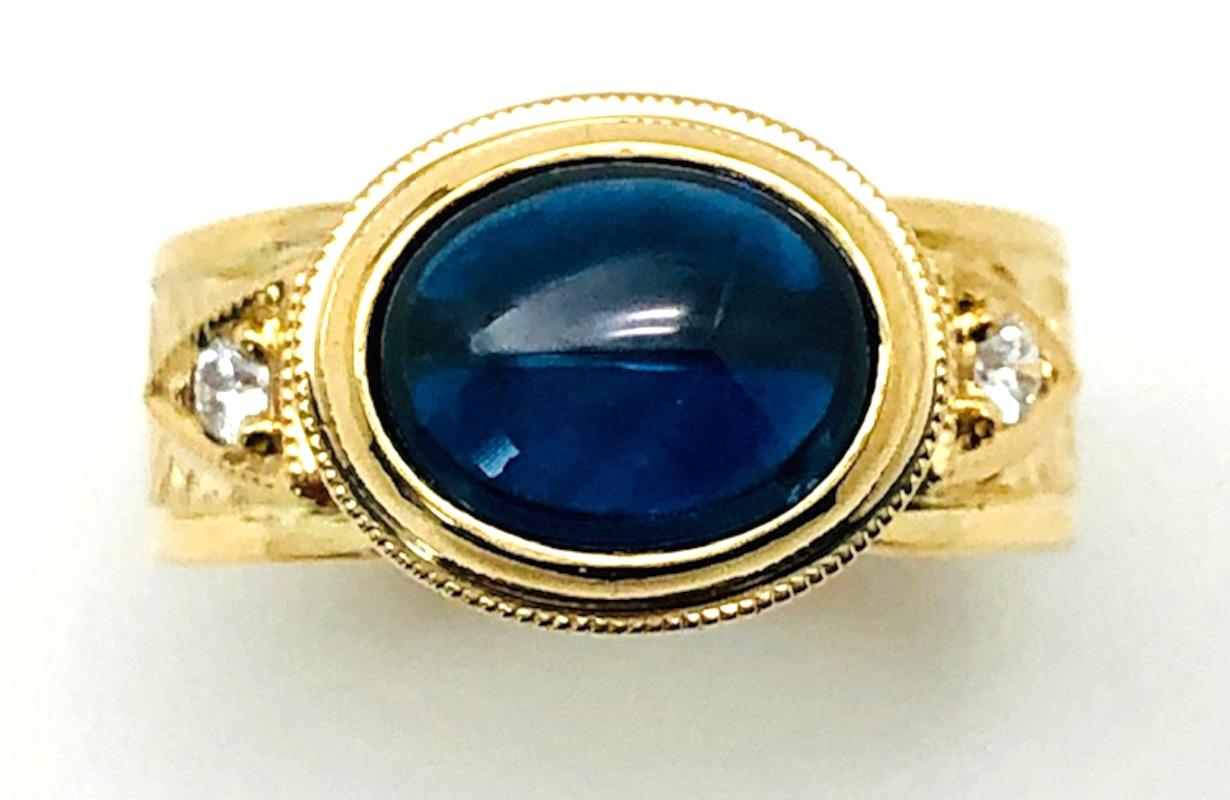 Handmade in 18k yellow gold, this gorgeous band ring features a beautiful oval blue sapphire cabochon which sits 